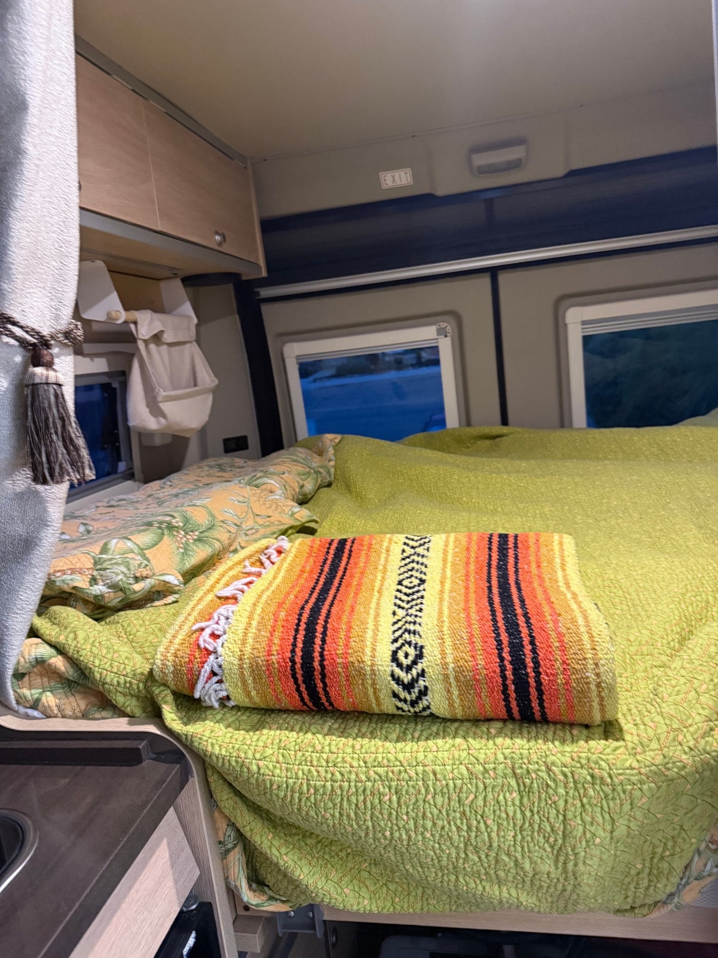 parked on a sunny street with scenic hills behind it.|Two dogs enjoy the outdoors with their RV rental. A scruffy terrier rests on a colorful blanket — photo 6