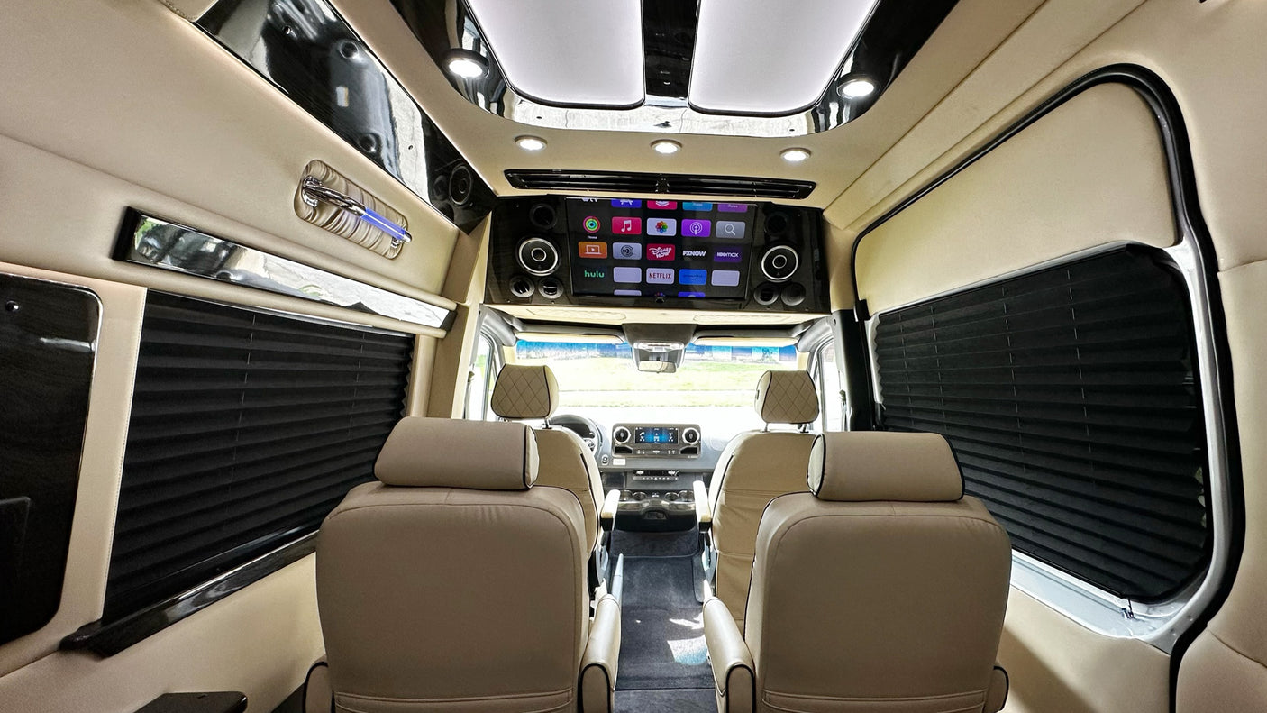 Inside a luxurious **rv rental**: cream leather seats, a large entertainment screen with apps, and sleek interior design for premium travel.