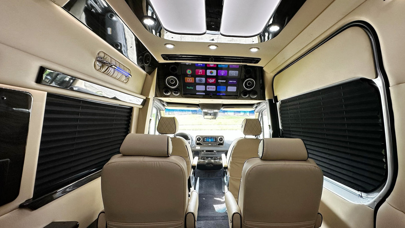 Inside a luxurious **rv rental**: cream leather seats, a large entertainment screen with apps, and sleek interior design for premium travel.