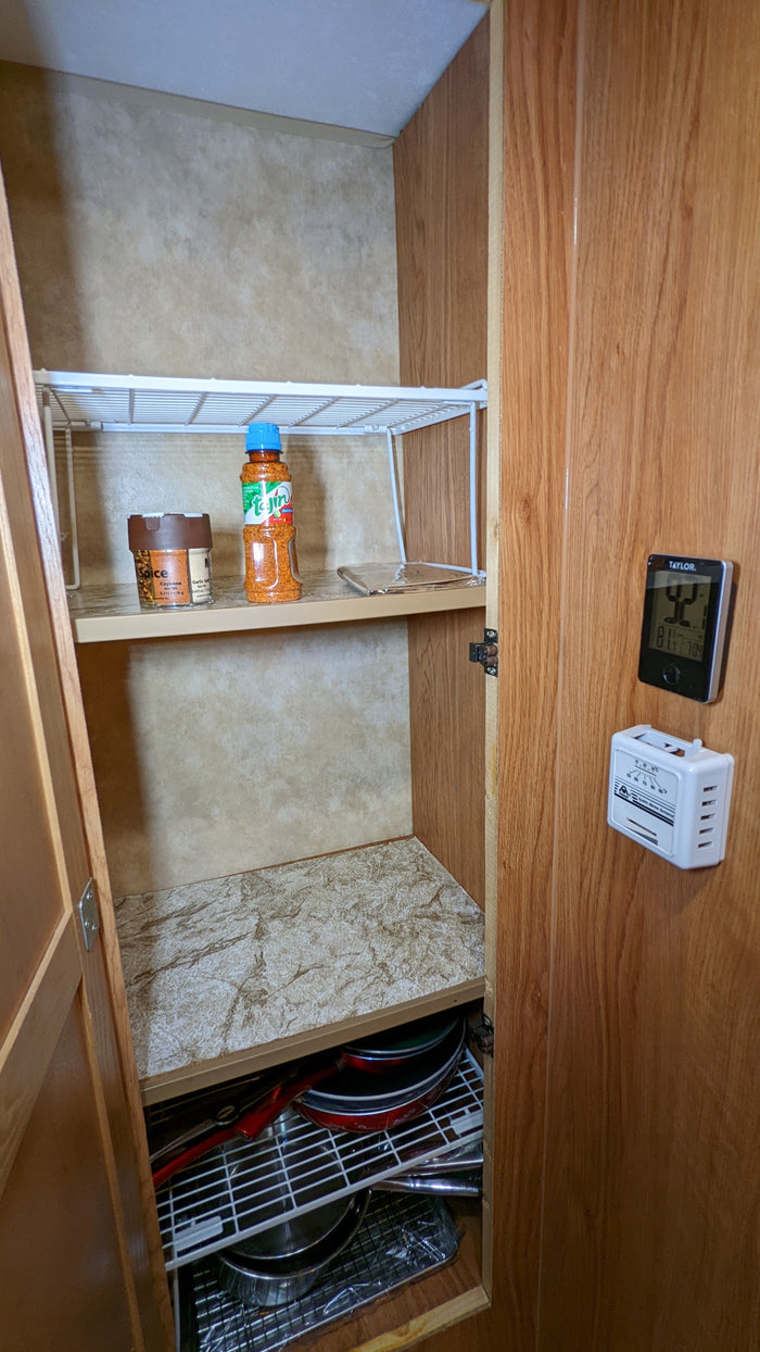 RV rental pantry cabinet: organized with spices, cookware on shelves, plus interior temperature displays.