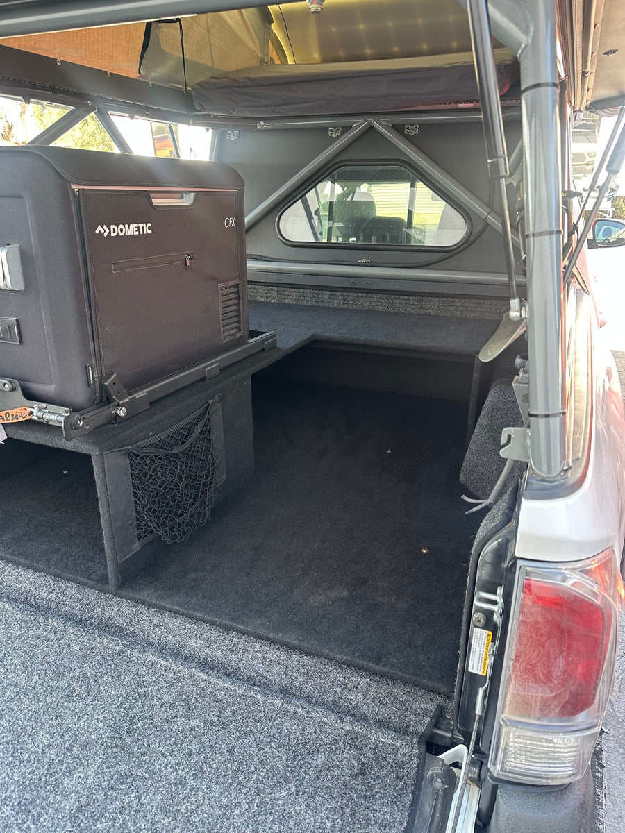 RV rental interior: Dometic fridge on slider, custom truck bed storage, and a sturdy pop-top camper shell.