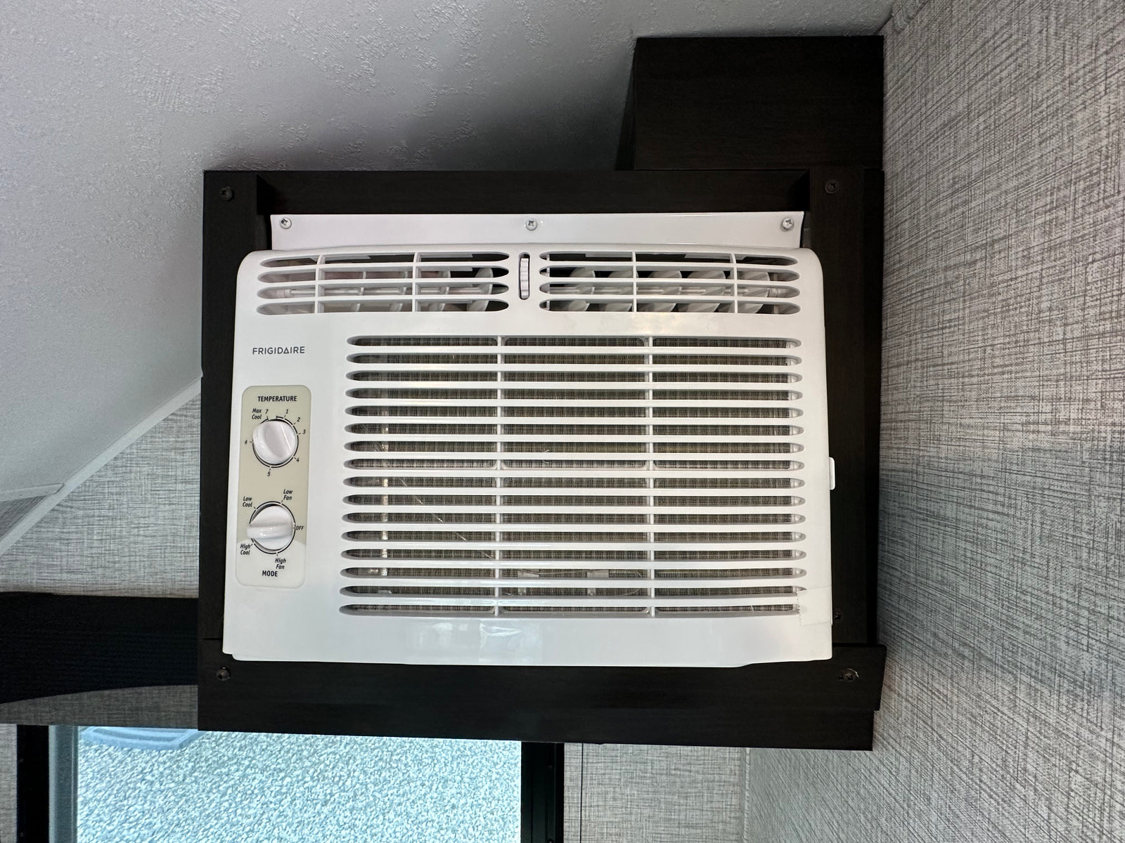 White Frigidaire AC unit, essential for comfort in your rv rental. Features temperature & fan mode controls for cool travel.