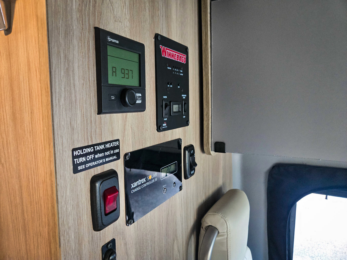 This RV rental interior shows control panels: Truma heater, Winnebago system, Xantrex solar, and holding tank heater switch.