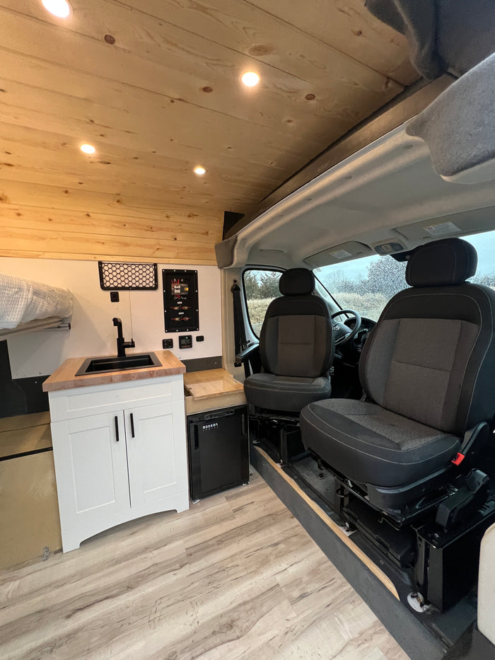 Clean RV rental interior with wood ceilings, a mini-kitchen, and front seats. Ready for your next adventure.
