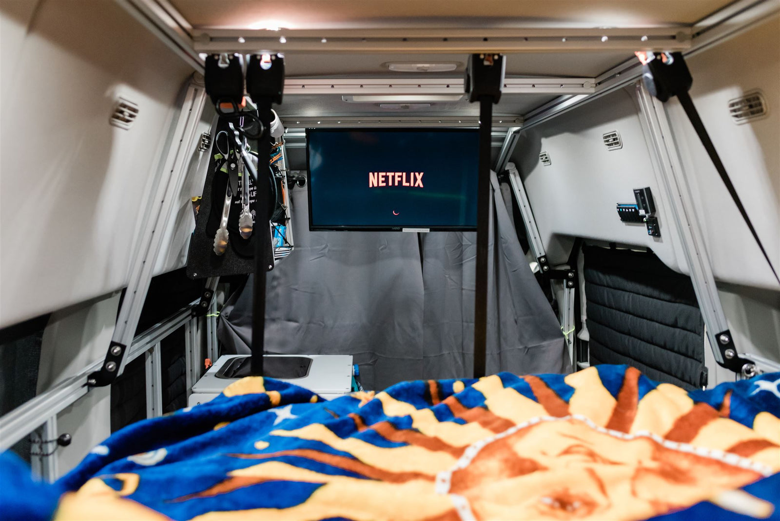 and organized kitchen space.|RV rental camper van interior. See the raised bed