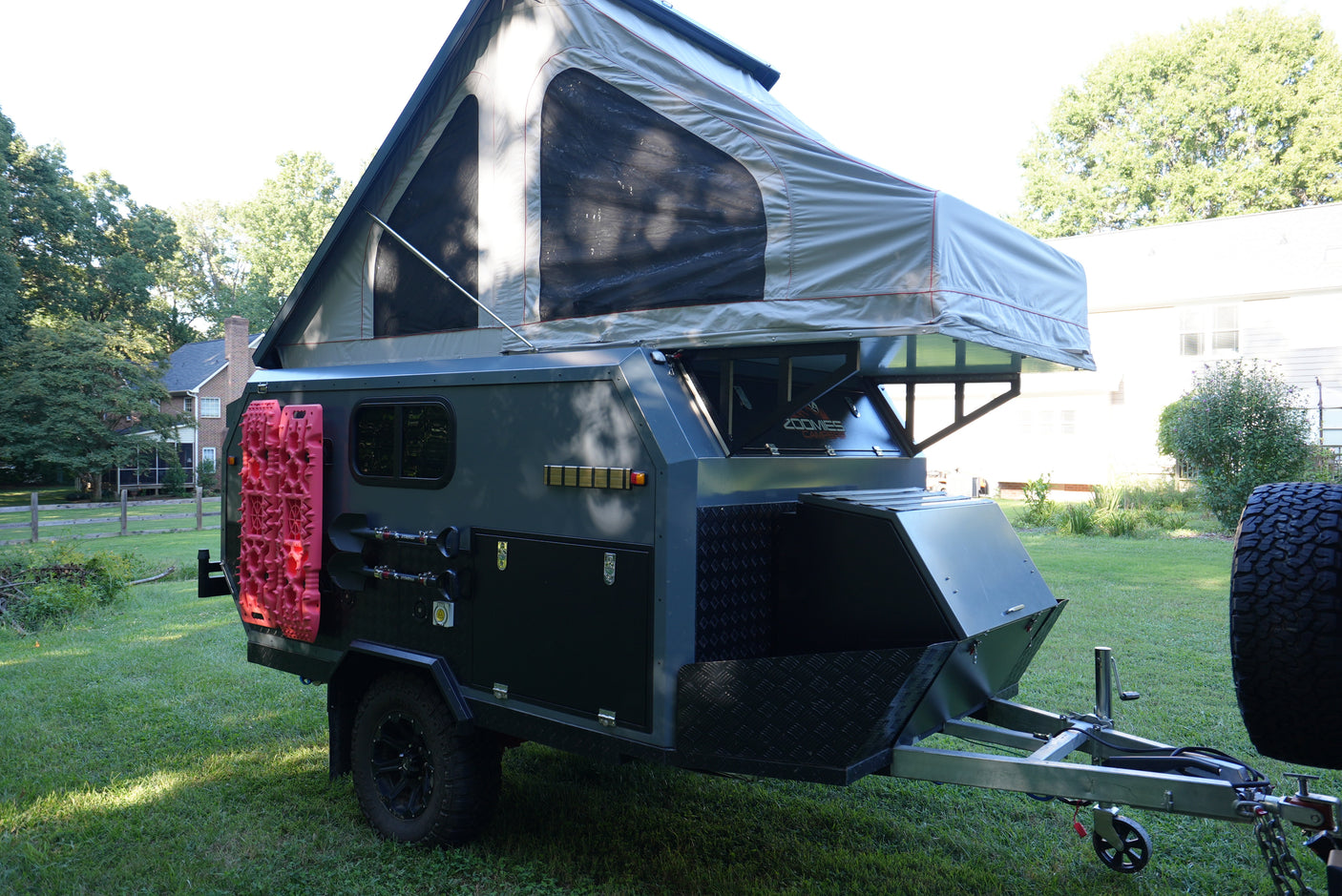 This rugged off-road camping trailer with a pop-up tent, ready for your next RV rental adventure, features mounted traction boards & shovels.