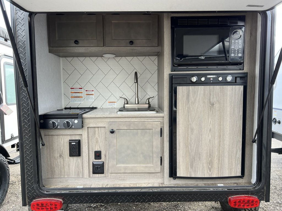 with a rugged tire visible on the left.|Explore a cozy RV rental interior: a modular bed with dark and white cushions