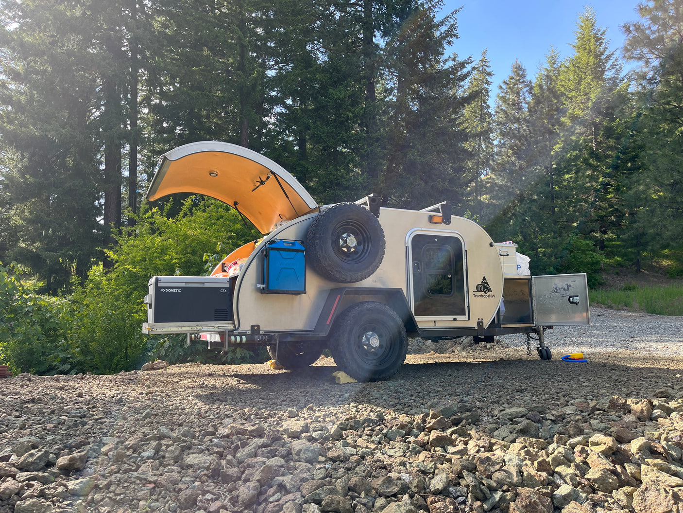 This teardrop camper, a perfect rv rental, features a Dometic fridge & Wavian container for forest camping.