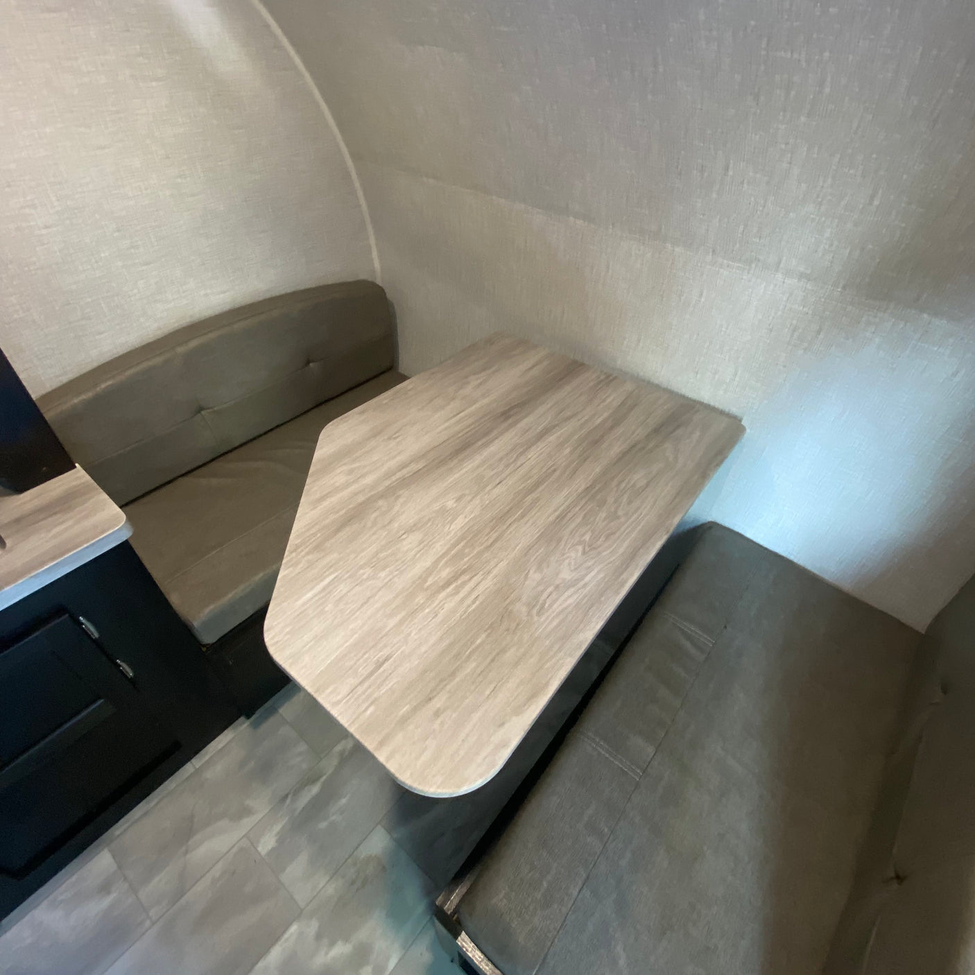RV rental interior featuring a dinette with a light wood table, upholstered bench seats, and textured walls.