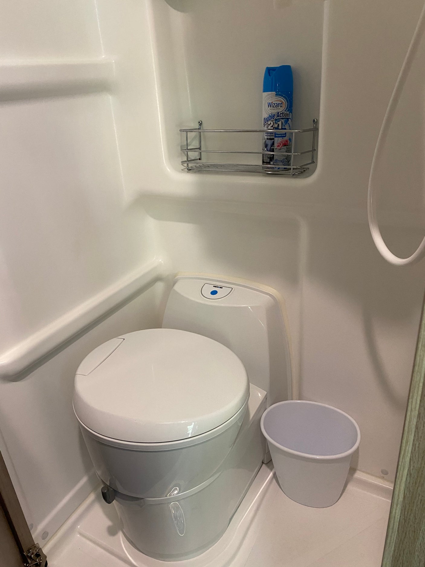 Compact RV rental wet bath with toilet, shower, and air freshener for comfort.