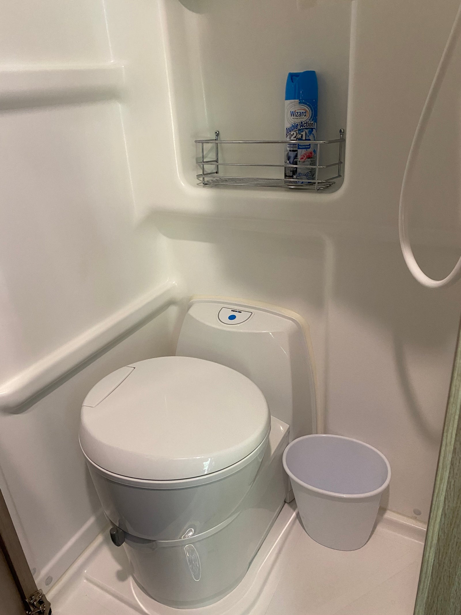 Compact RV rental wet bath with toilet, shower, and air freshener for comfort.