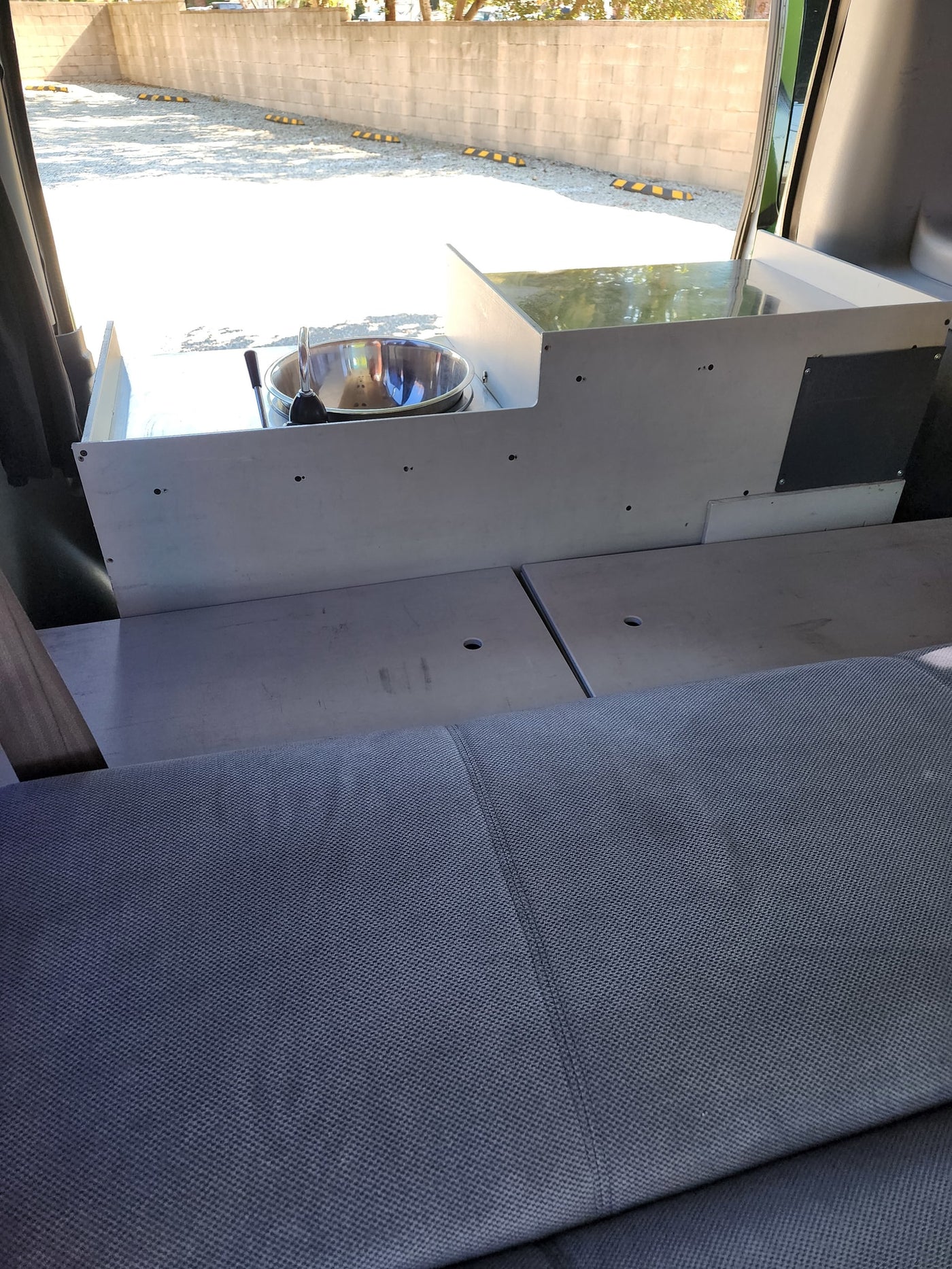 RV rental interior with a custom-built unit featuring a stainless steel sink and faucet, alongside gray fabric seating or a bed. — photo 11