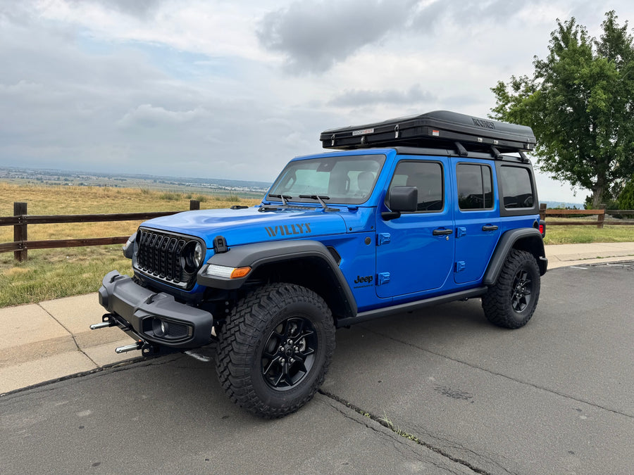 Blue Jeep Wrangler with rooftop tent, great for **RV rental** trips & overlanding adventures in the outdoors.