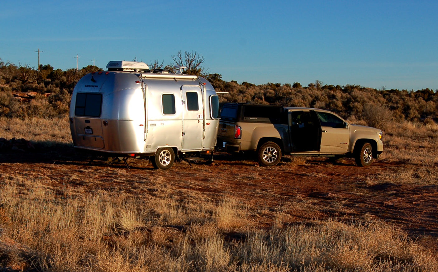 Explore the outdoors with an RV rental: An Airstream trailer hitched to a pickup truck in a scenic, arid landscape.