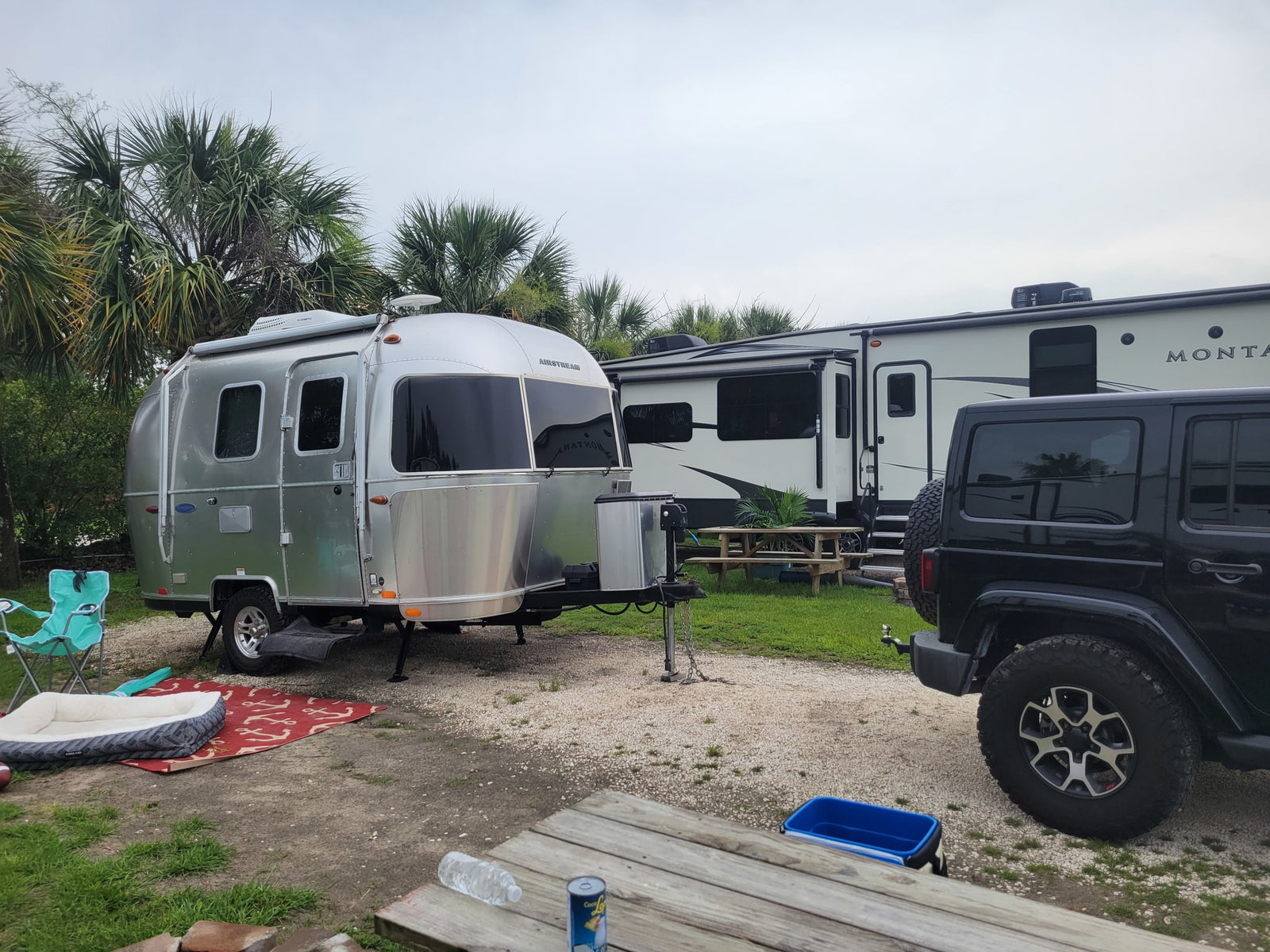 Serene rv rental campsite featuring a silver Airstream, a large Montana fifth-wheel RV, and a black Jeep parked.