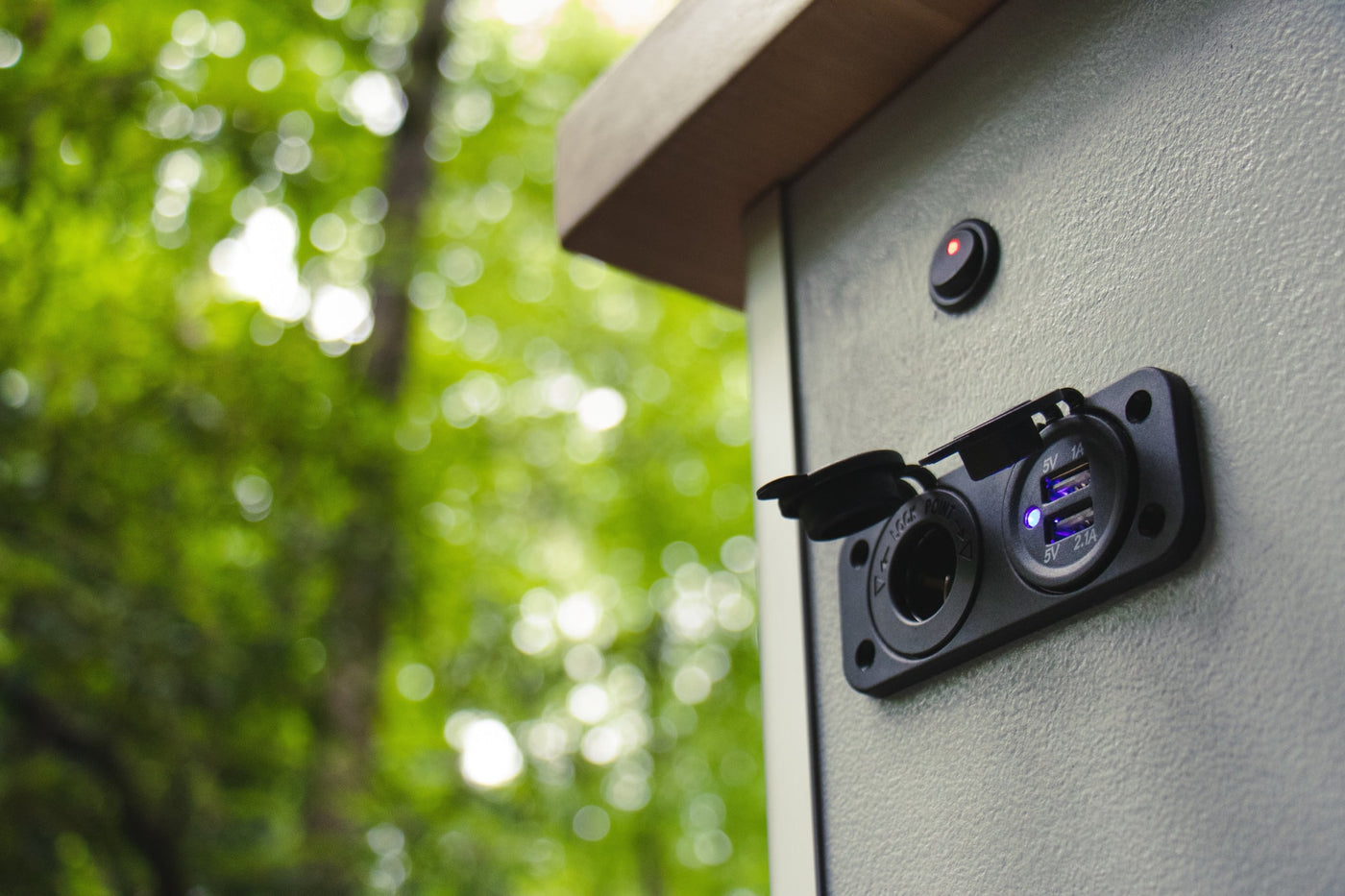RV rental: Exterior power panel with active blue USB charging ports and a 12V socket on a grey textured surface, ideal for outdoor use. — photo 9