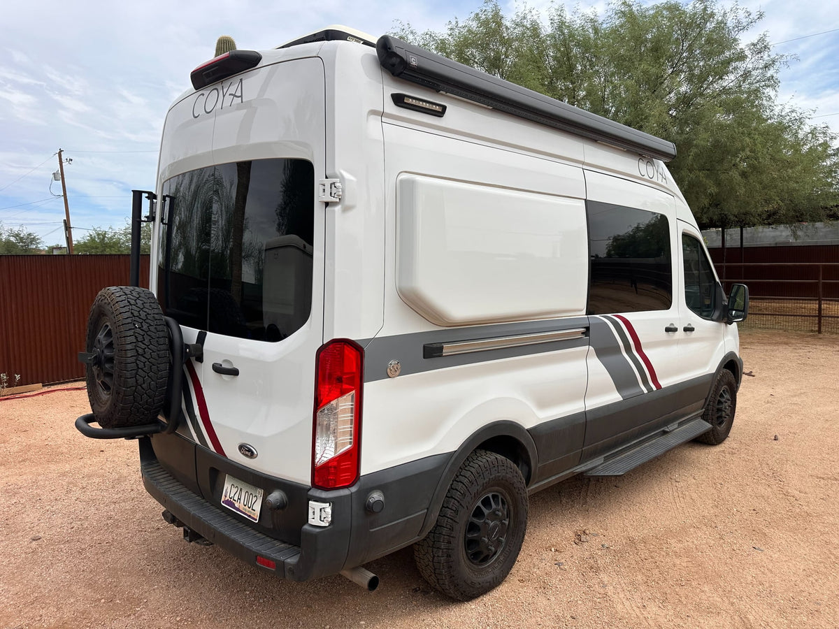 equipped for adventure. Parked on gravel in a desert landscape.|White COYA rv rental: a Ford Transit camper van — photo 2