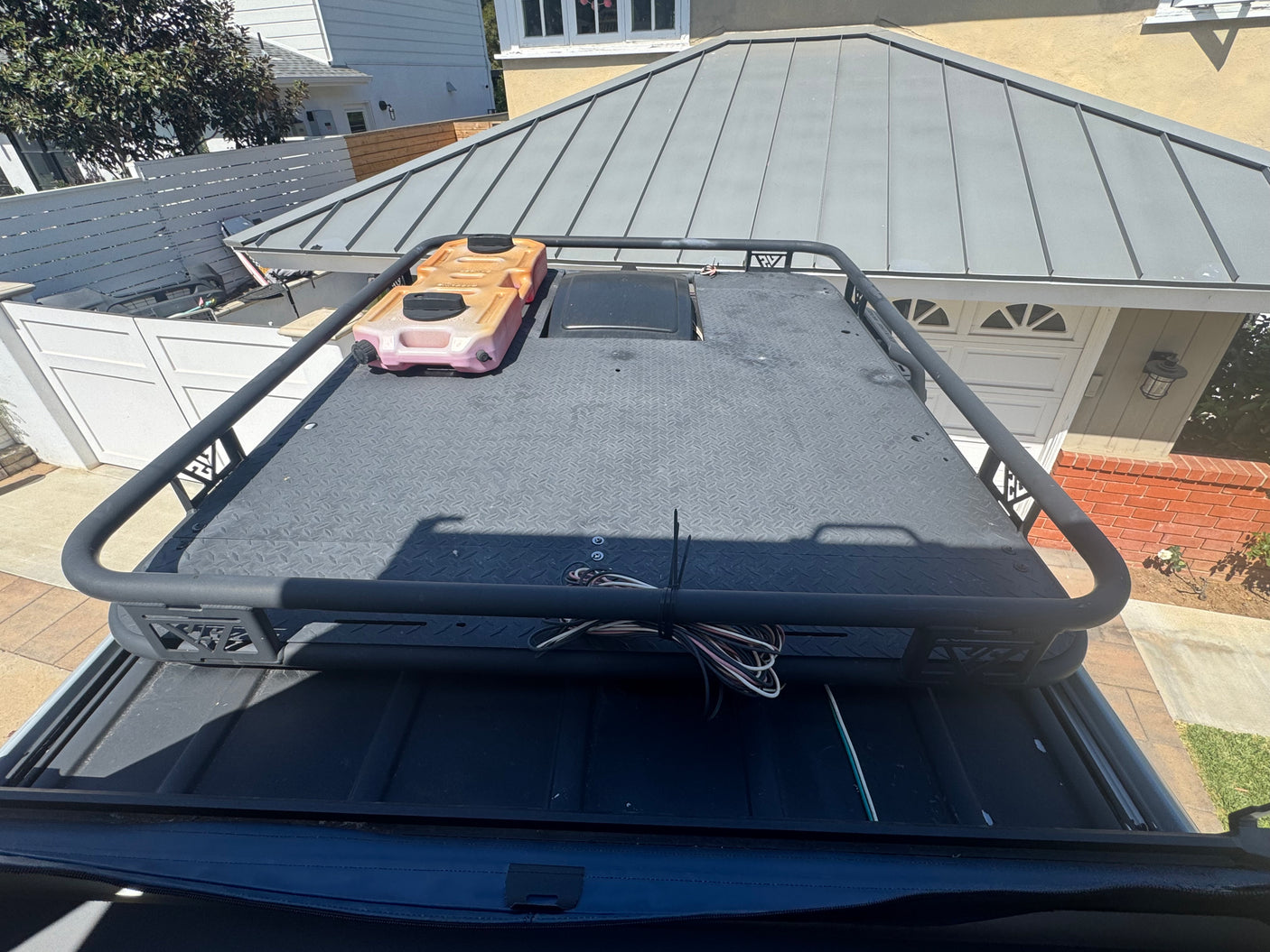RV rental: Overland roof rack with fuel/water container & bundled wires on a textured platform, ready for adventure.