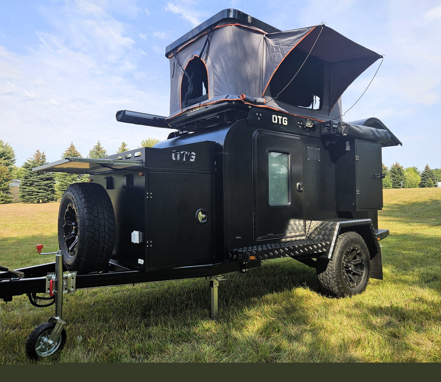 Black OTG overland camper trailer with rooftop tent deployed