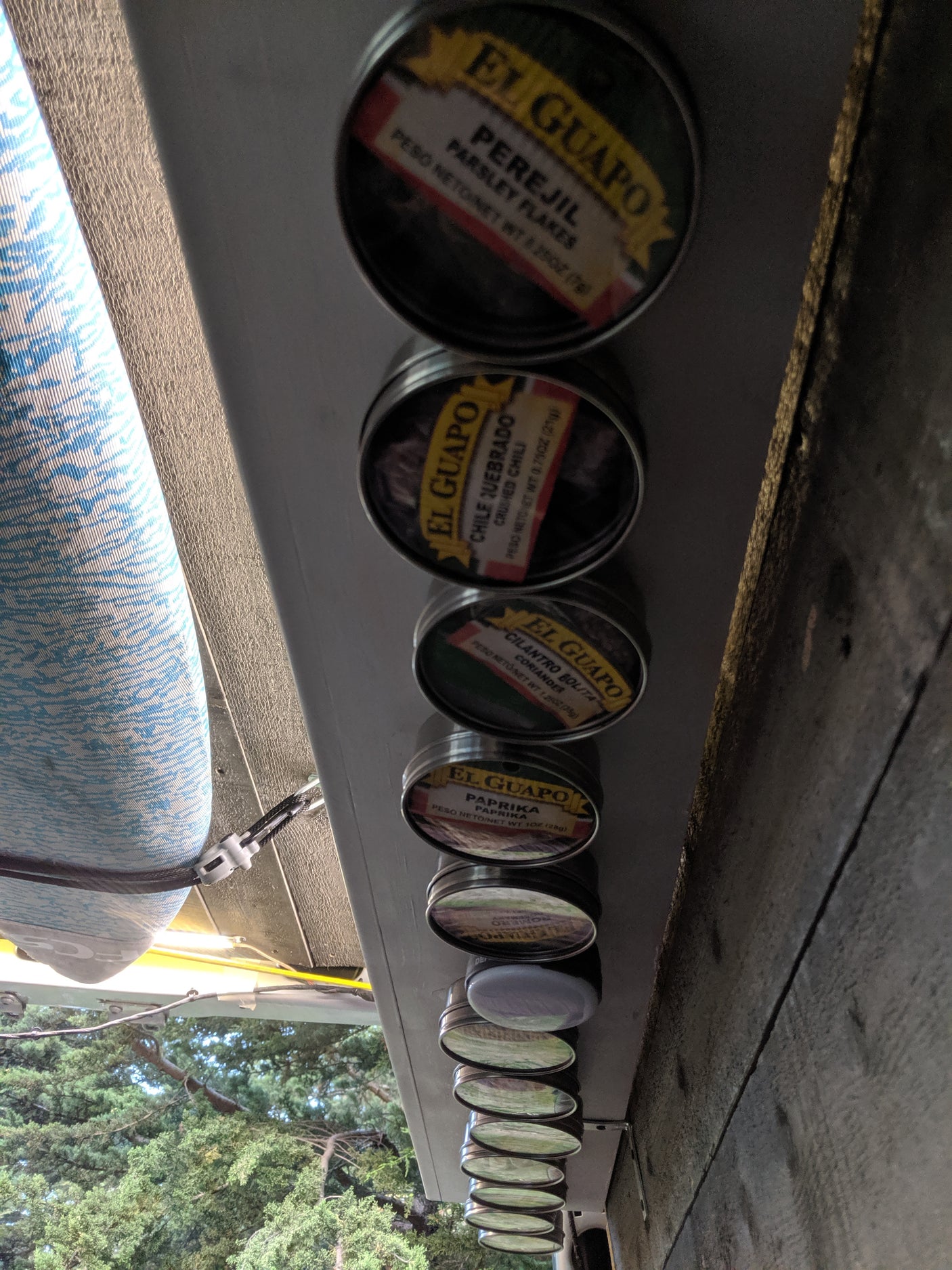 RV rental kitchen showing magnetic El Guapo spice tins (parsley, chili, coriander, paprika) for organized cooking on the go.