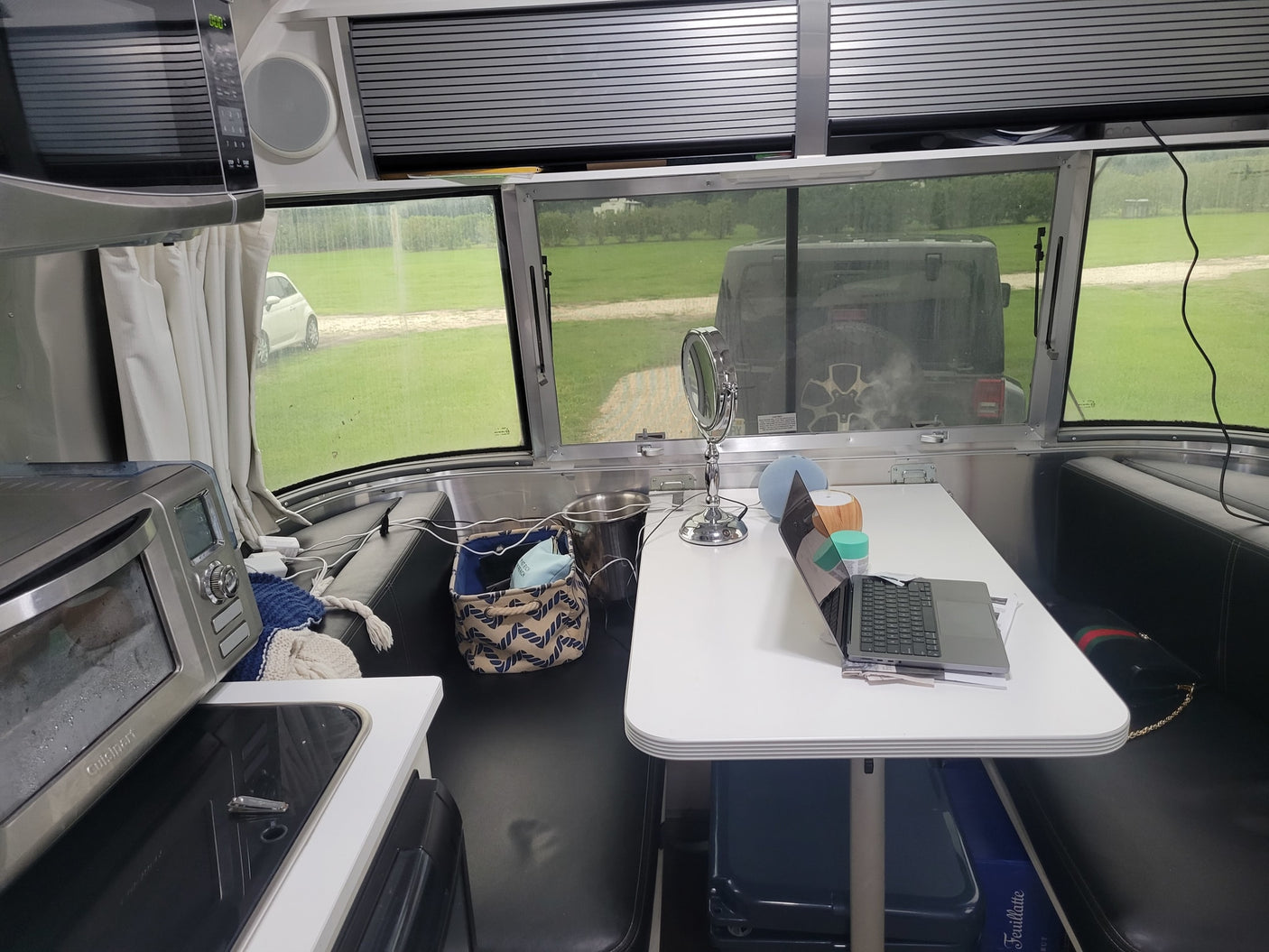RV rental interior: A bright, modern camper with kitchen appliances, dining table, laptop workstation, and outdoor views.