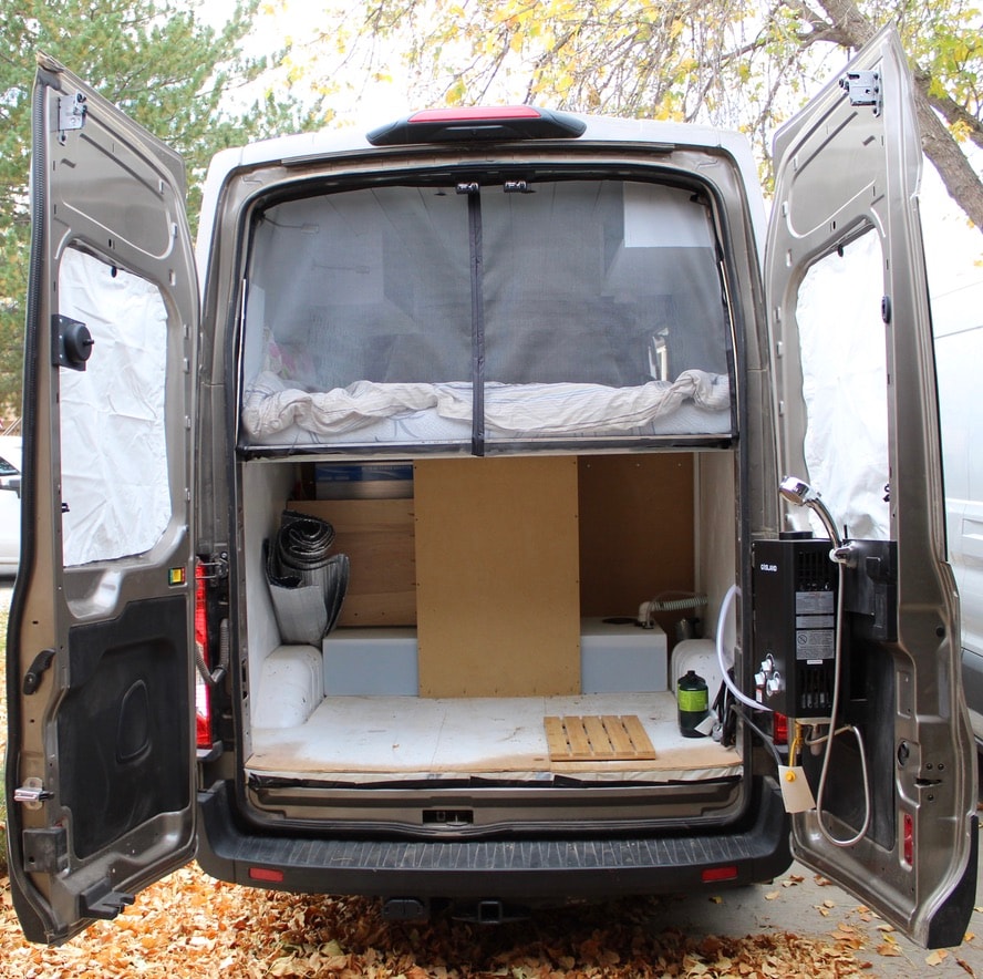 next to a raised bed.|Custom RV rental interior: teal kitchen