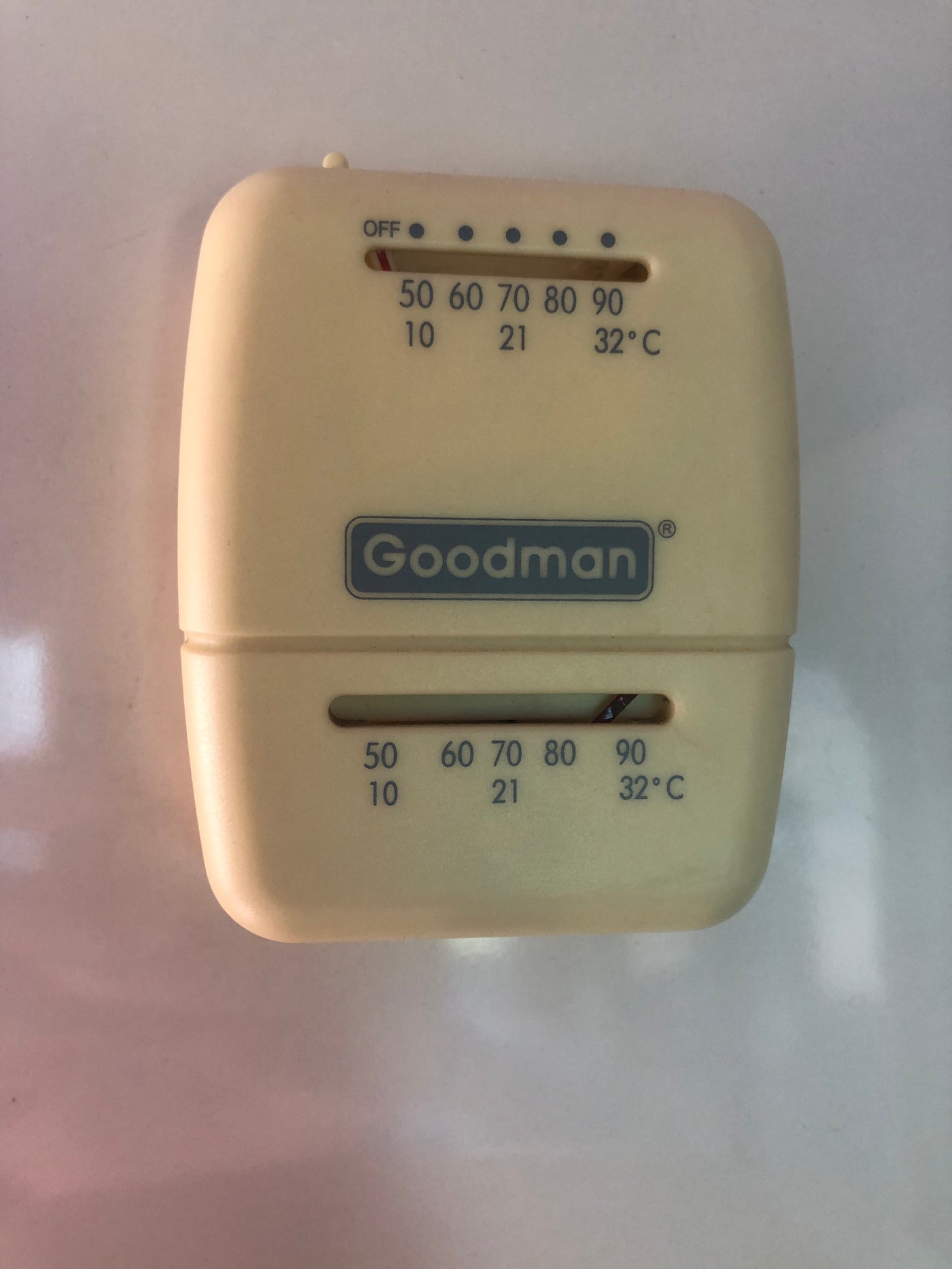 This Goodman analog thermostat in an RV rental controls temperature, showing Fahrenheit and Celsius settings for climate control.