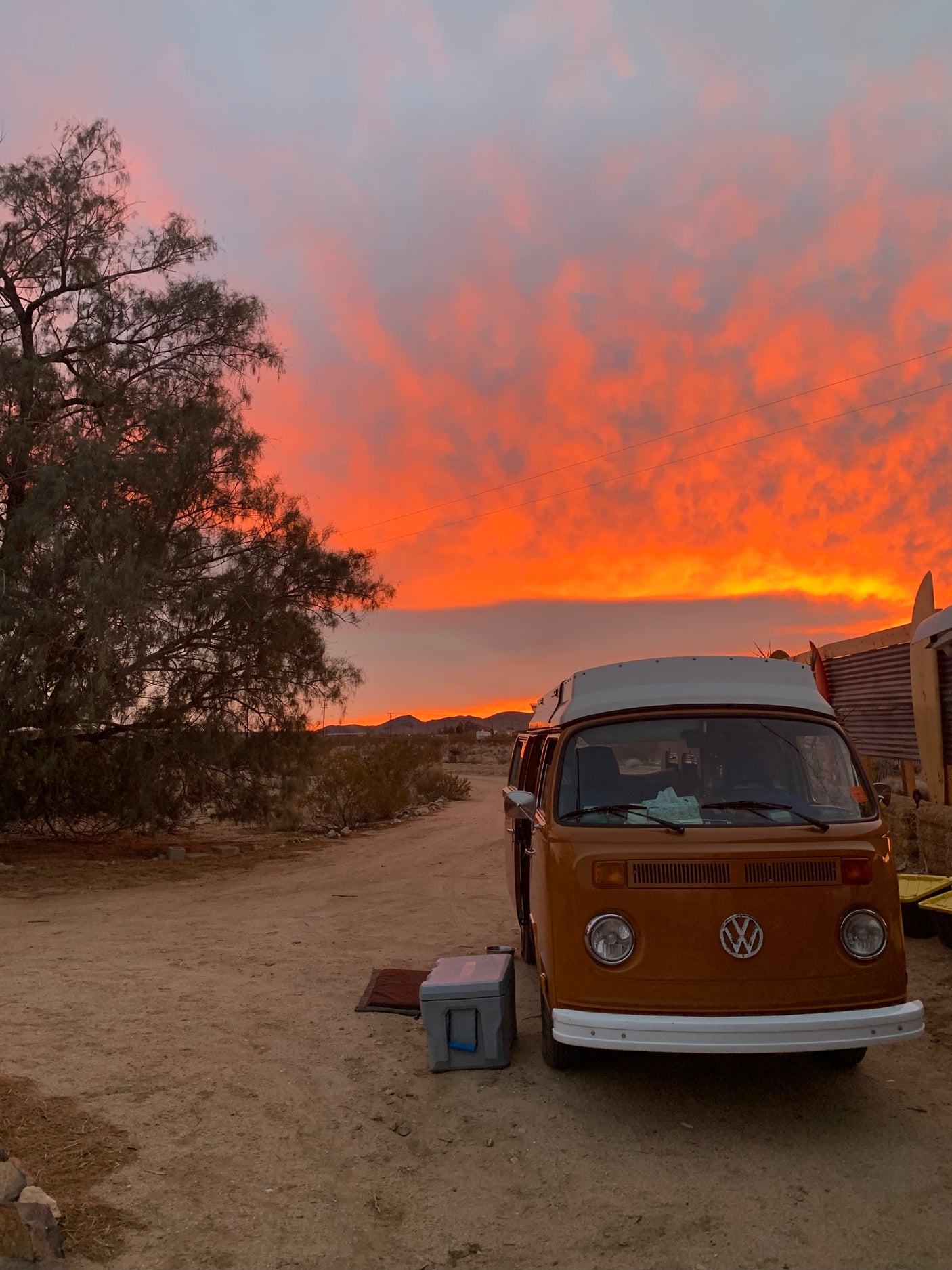 Classic orange VW camper van under a brilliant orange desert sunset. Ready for your next RV rental adventure.