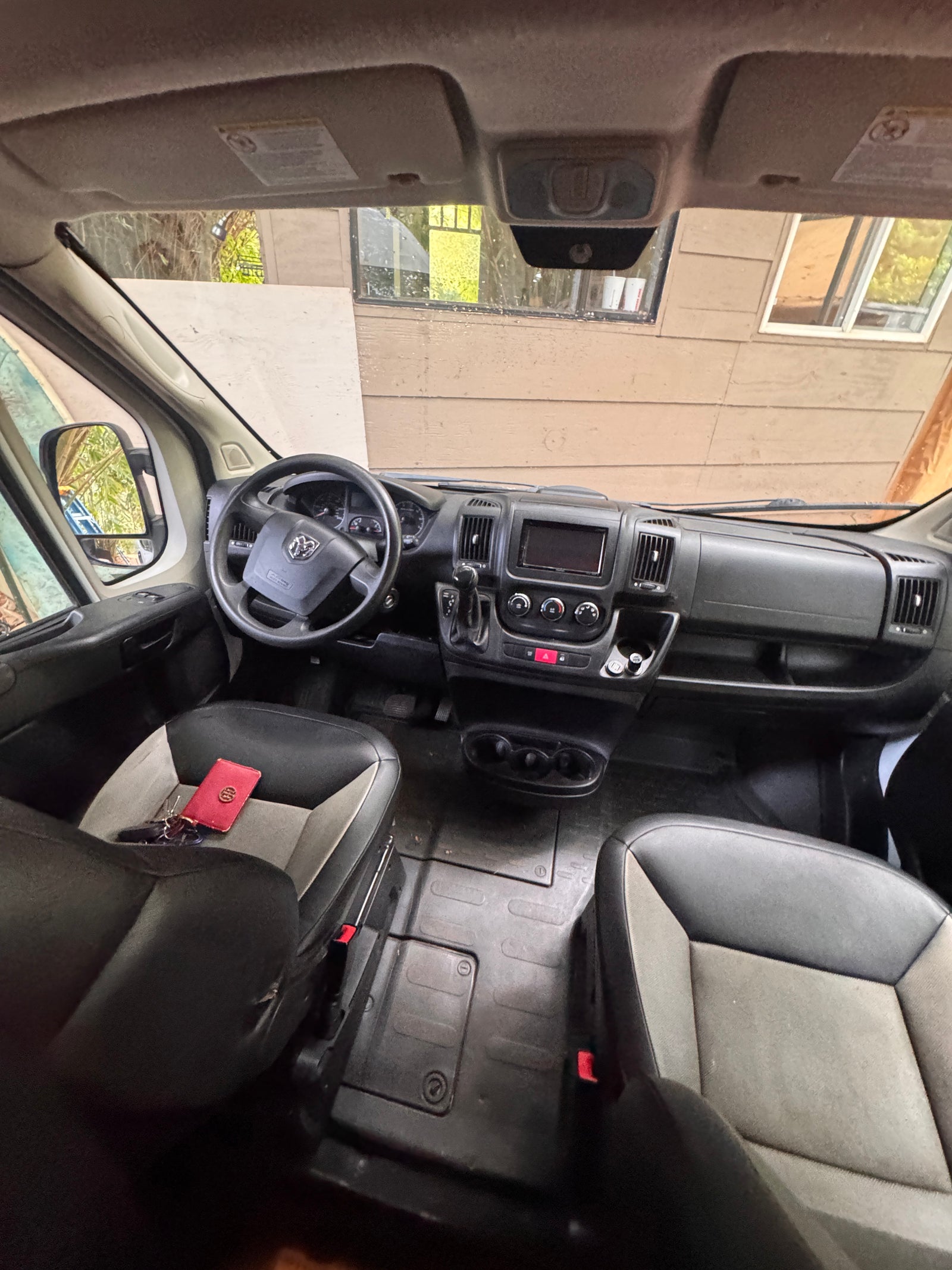 Ram ProMaster rv rental van interior: cockpit view with dashboard, steering wheel, and front seats holding keys.