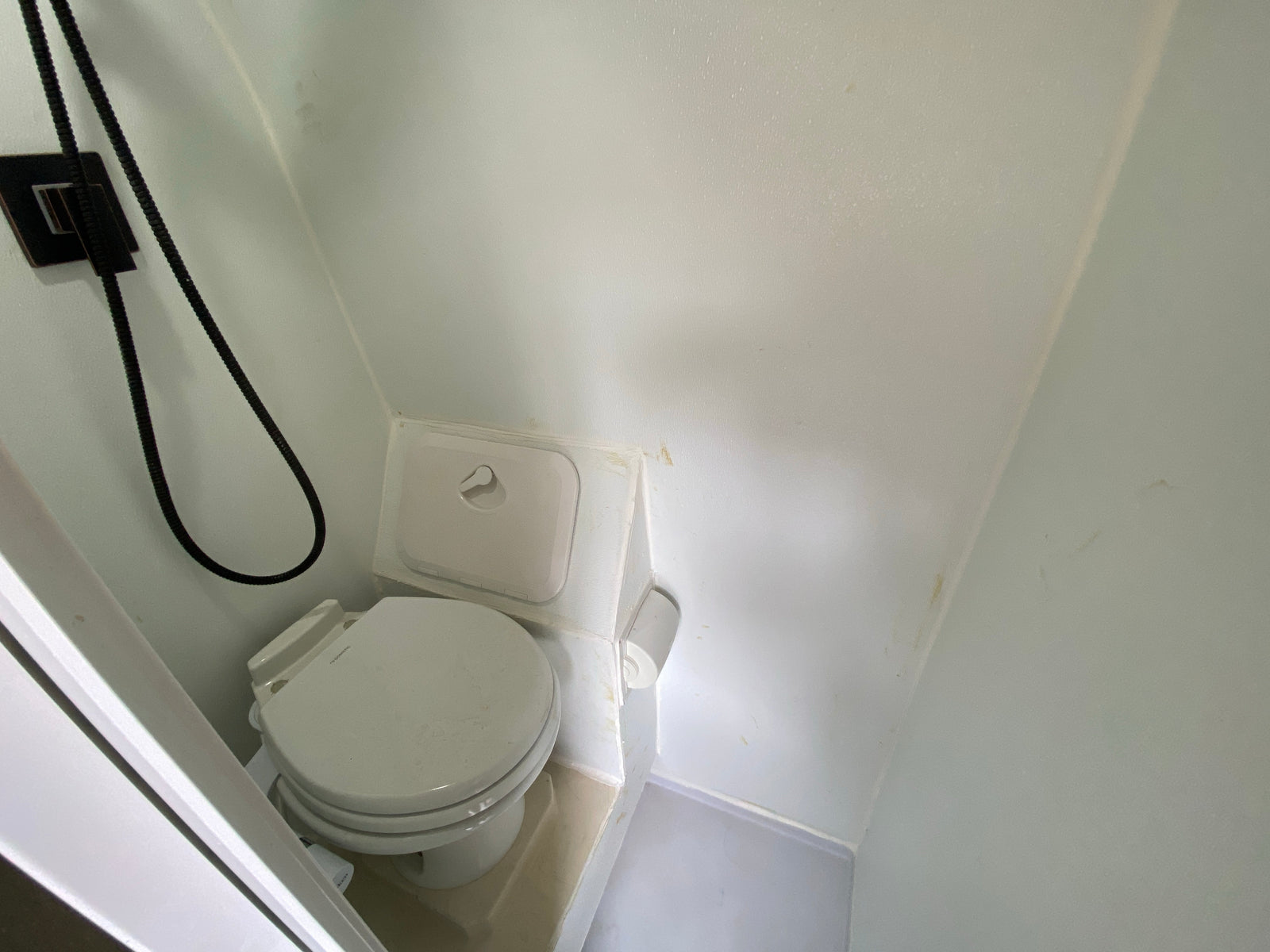 This RV rental features a compact, functional bathroom with a white toilet and shower, showing signs of use.