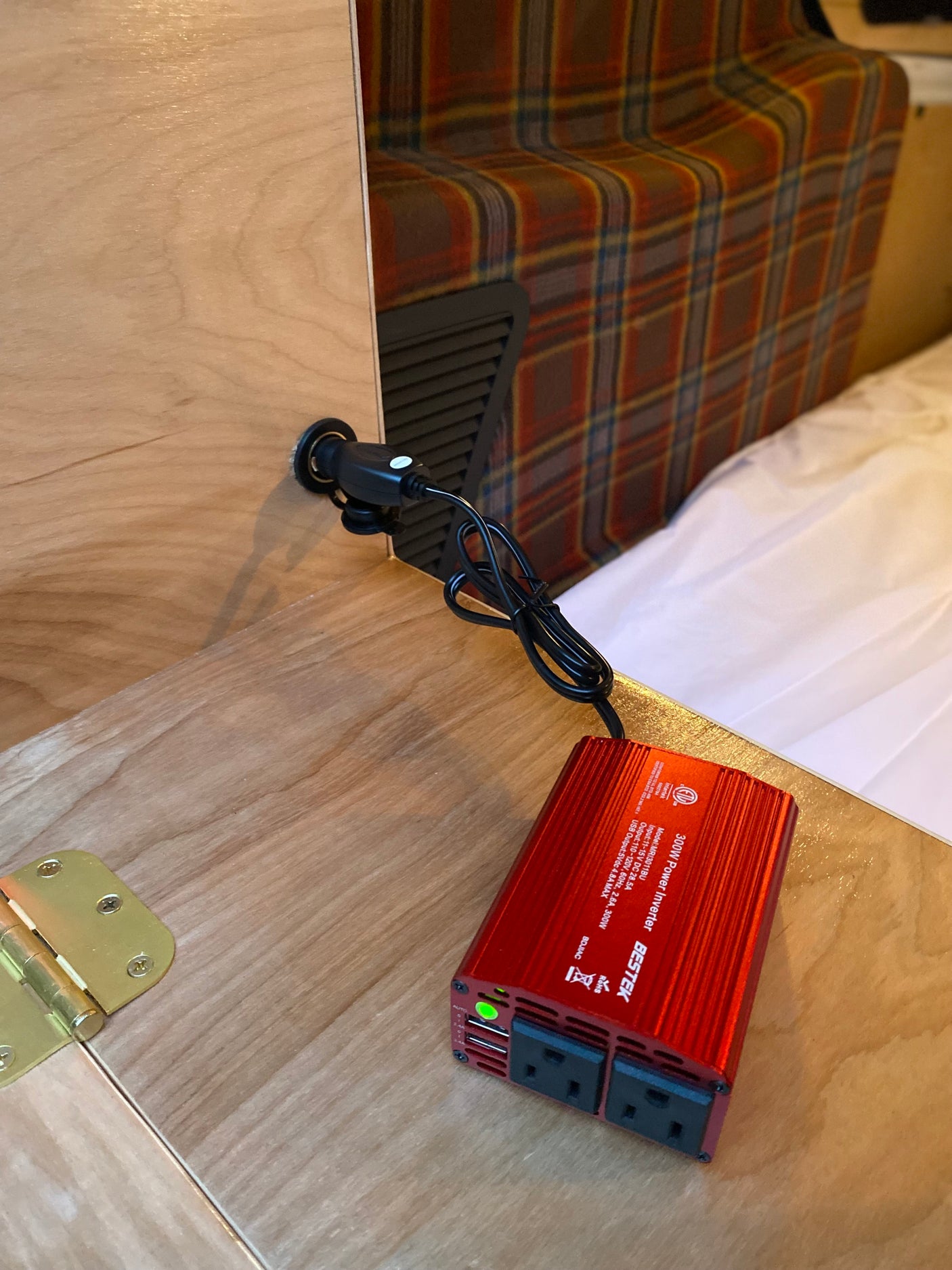 Red BESTEK 300W power inverter connected to a 12V socket in an rv rental, providing AC and USB power for devices.