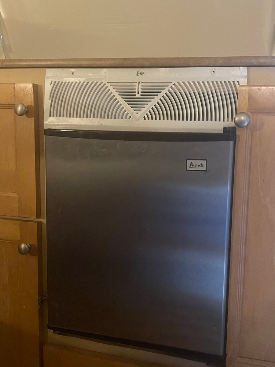 Compact Avanti mini-fridge/ice maker for RV rental kitchenette, built into light wood cabinetry with knobs.