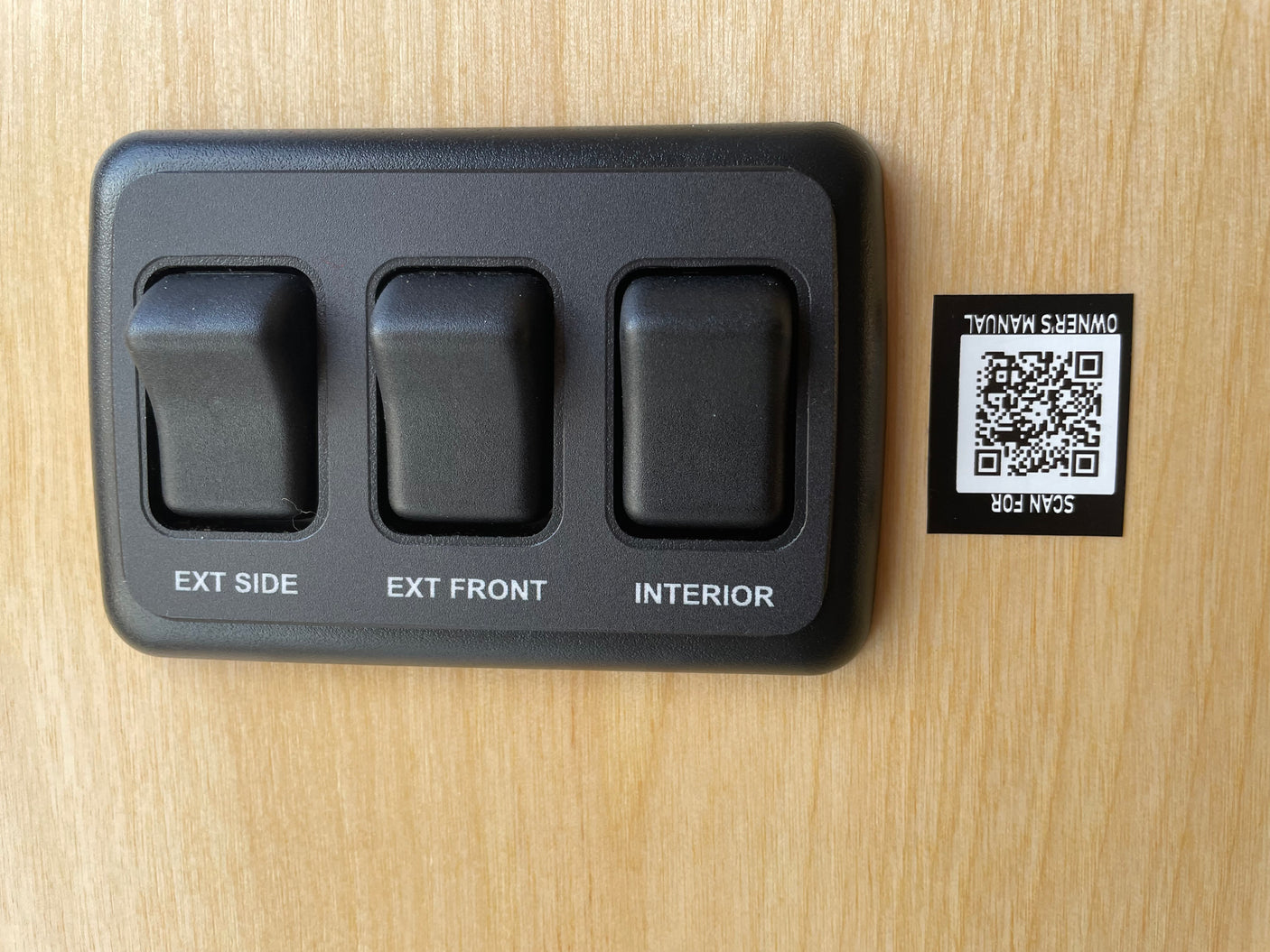 RV rental controls: switches for exterior side, front, and interior lights. Scan QR for owner's manual.