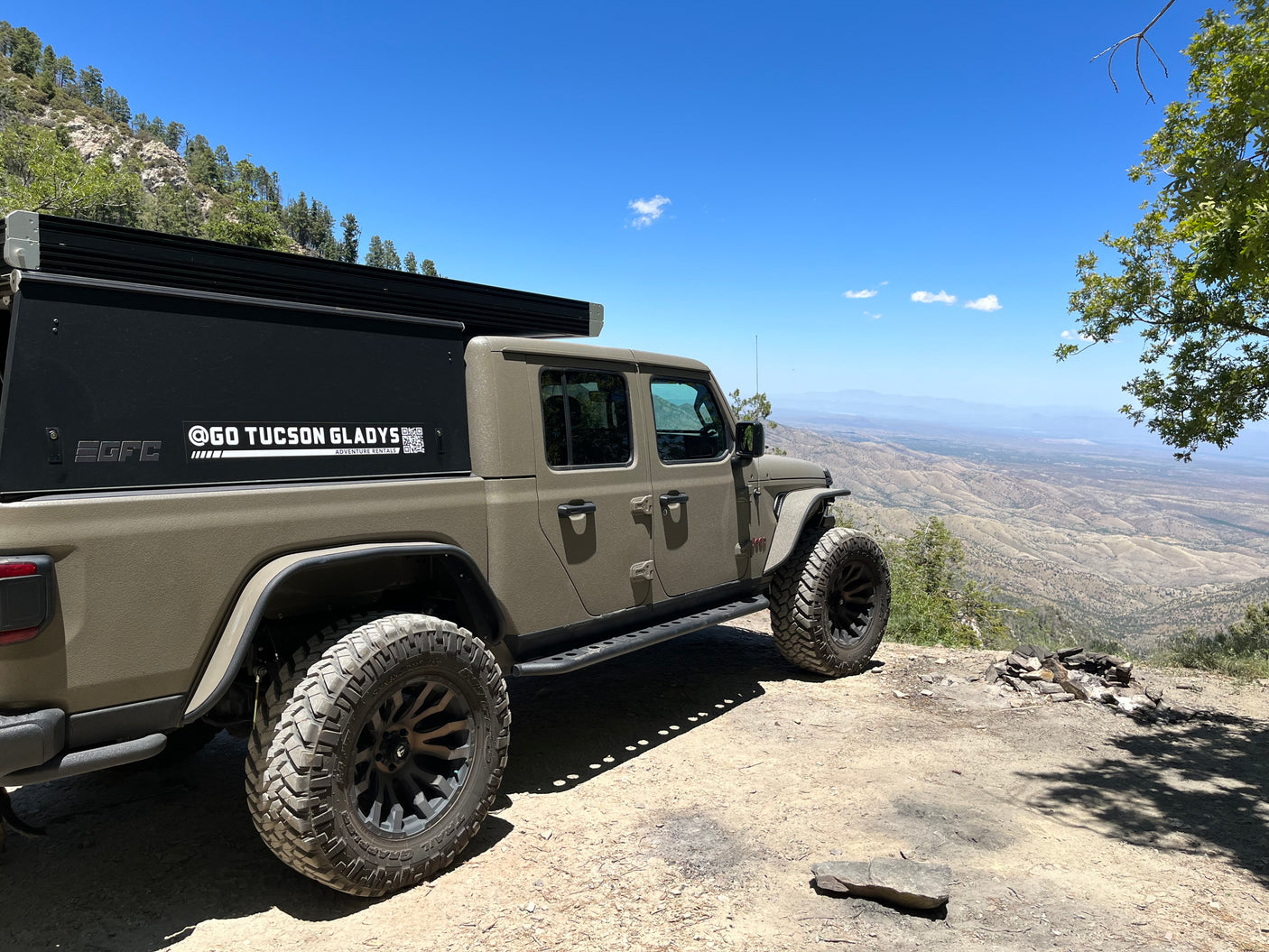 Explore with this Go Tucson Gladys RV rental Jeep Gladiator with truck camper, parked high above vast desert mountain views.