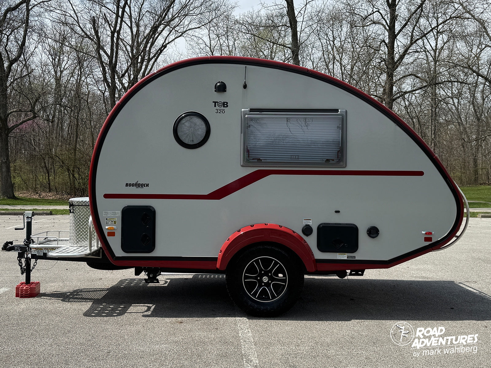 This white T@B 320 Boondock teardrop camper, featuring red trim and fender, is ready for your next rv rental trip.