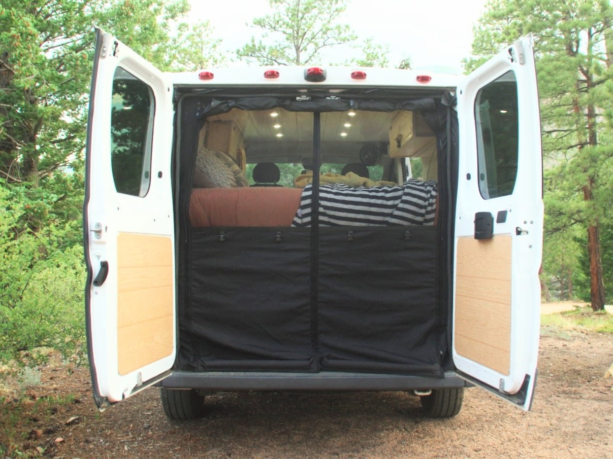 and a Jeep visible outside.|Cozy RV rental view from inside: tall pine trees — photo 13