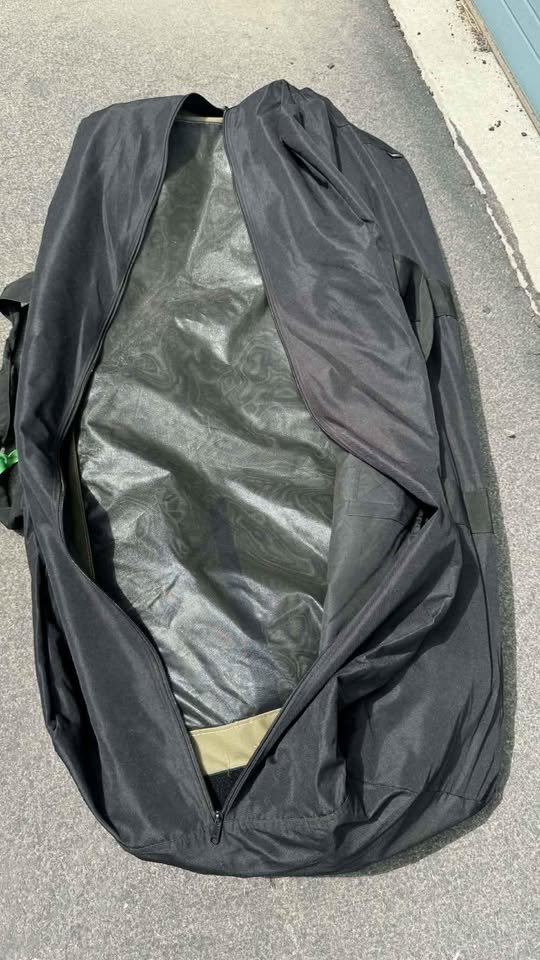 Bush Company awning storage bag unzipped on the pavement, included with the trailer — photo 19