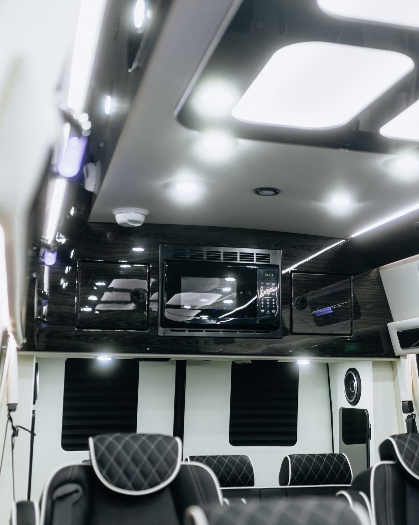 Luxurious RV rental interior: microwave, quilted seating, and sleek LED lighting for your comfort.