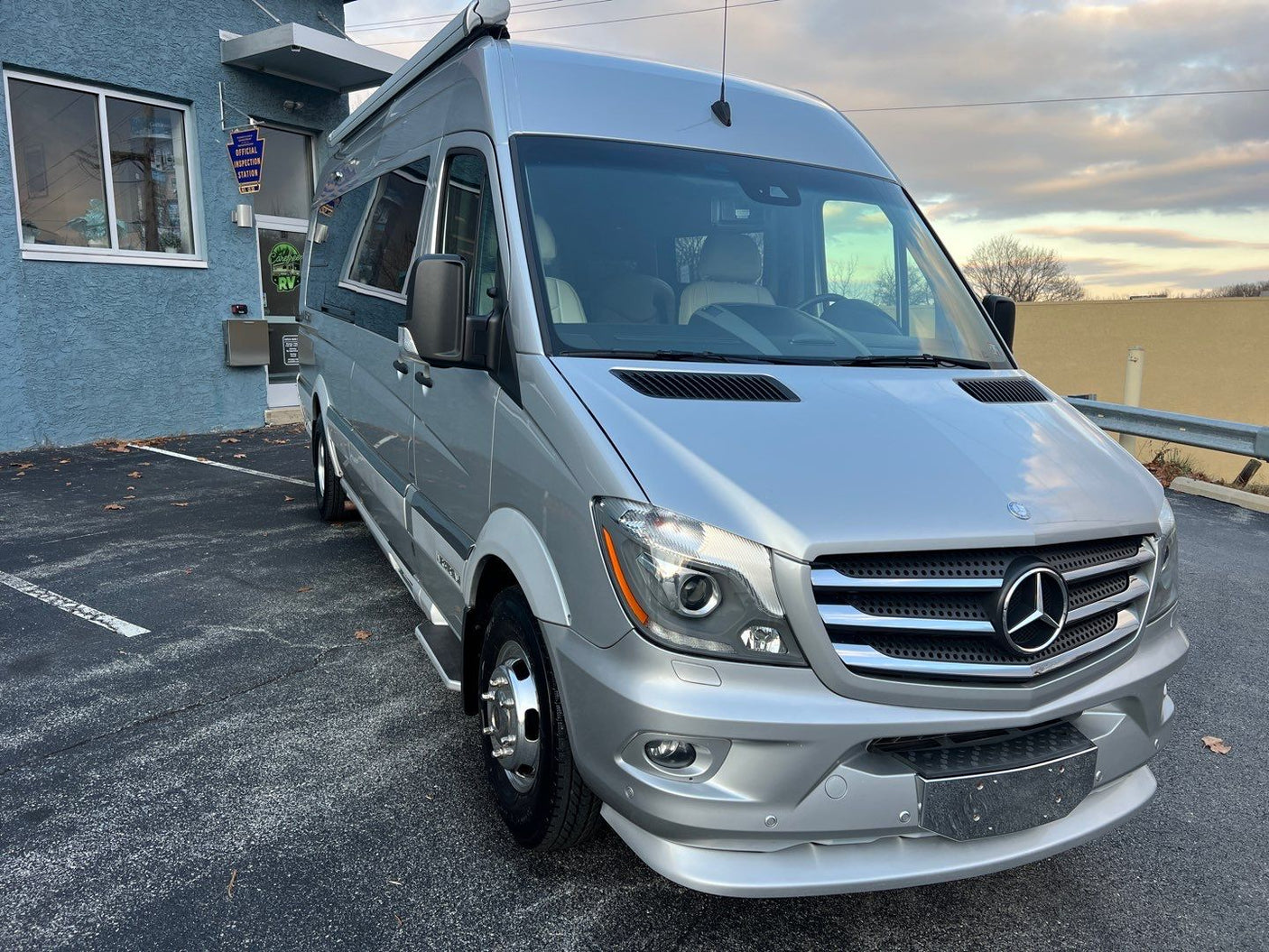 A silver Mercedes-Benz Sprinter RV, an rv rental vehicle, parked at a service station.