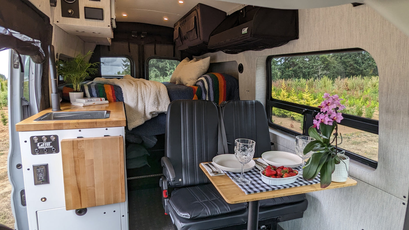 This modern RV rental interior offers a comfortable, compact living space with a kitchen, dining area, and cozy bed for travel adventures.