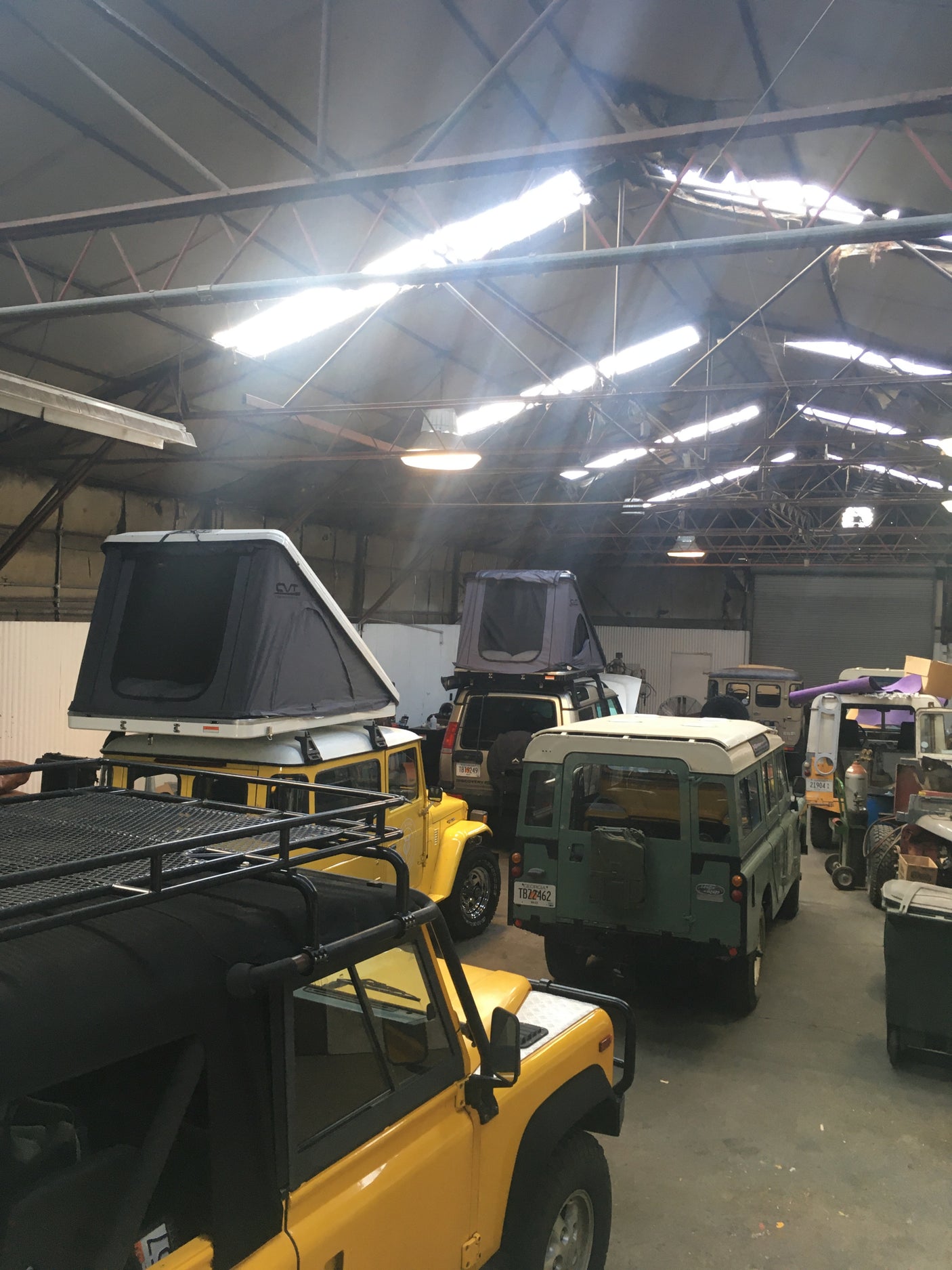 Inside a spacious garage, multiple overlanding SUVs with rooftop tents, ideal for an RV rental adventure, await off-road journeys.
