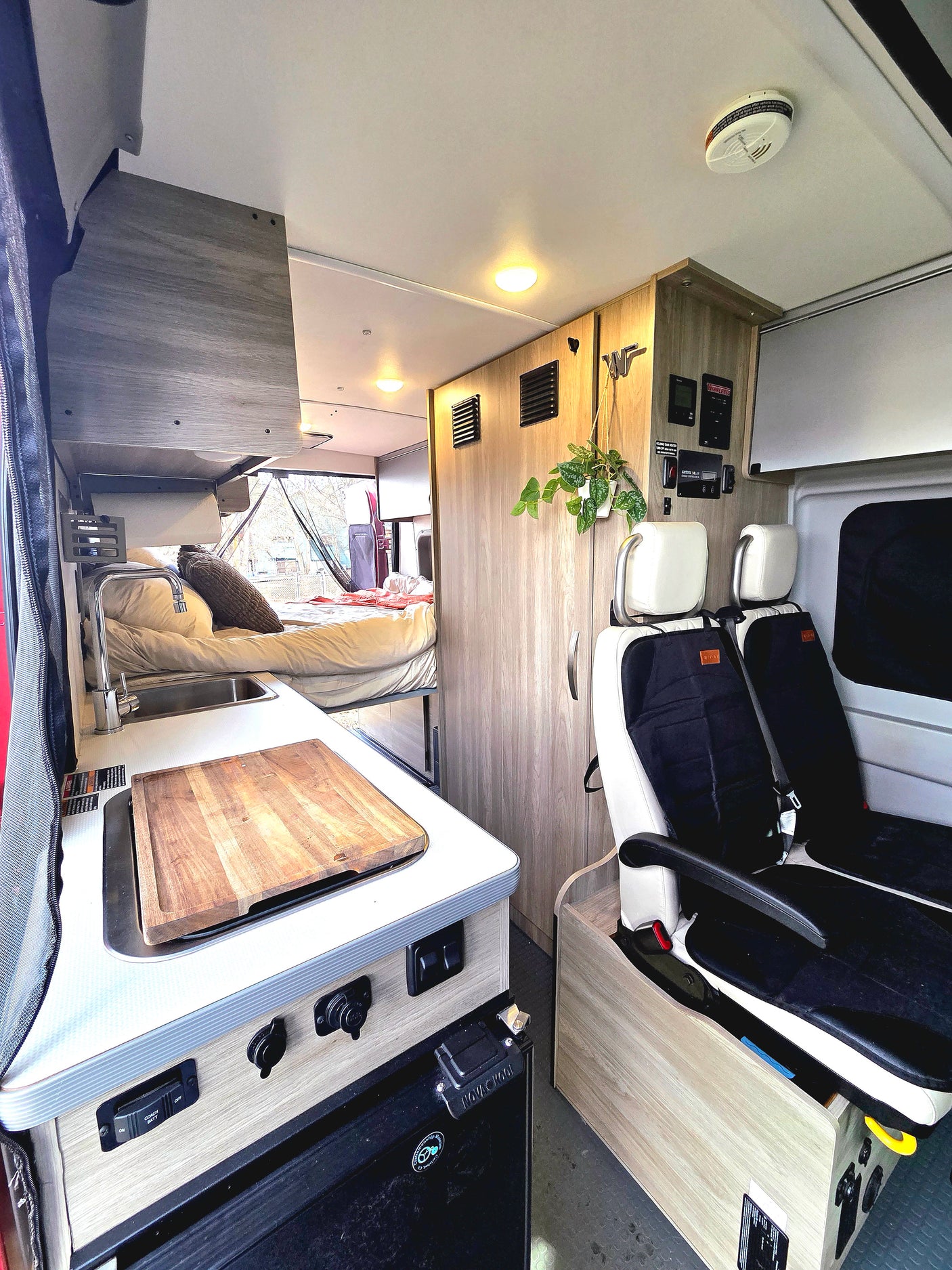 This RV rental features a well-equipped campervan interior with kitchen, bed, seating, and controls. Compact and ready for travel.