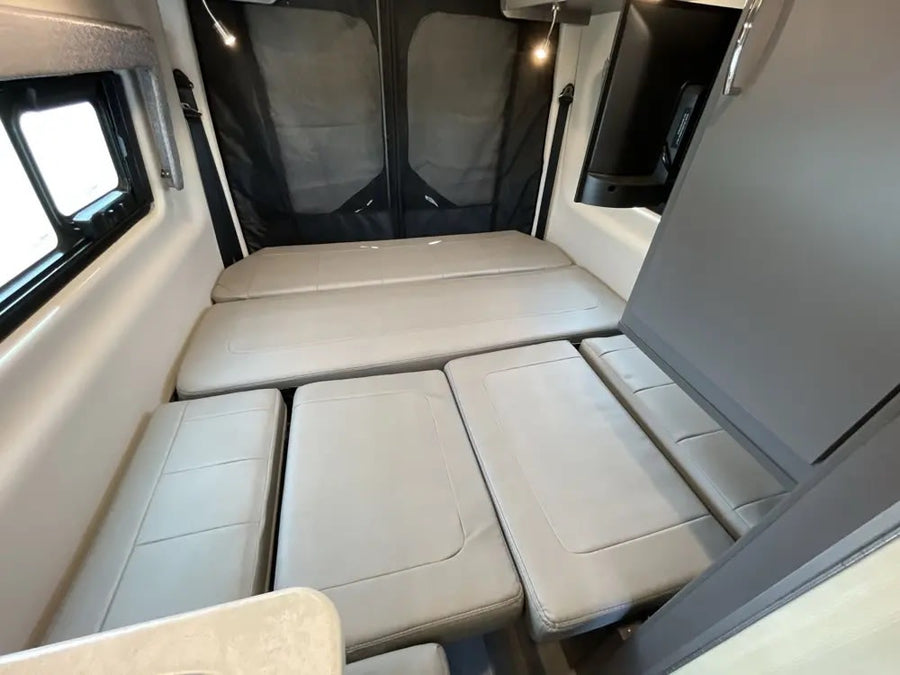 parked in a sunny outdoor lot with other RVs under a clear sky.|Inside an RV rental: front cockpit view with a black steering wheel