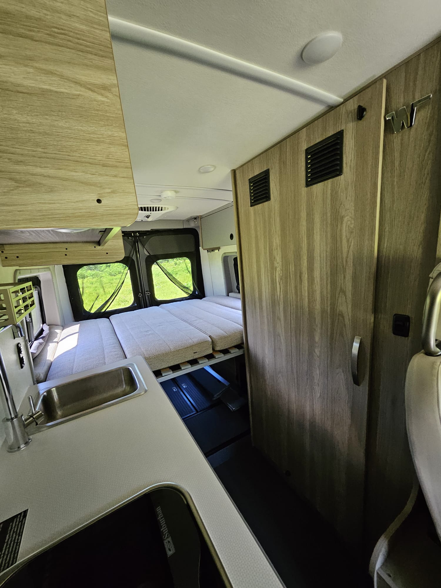 and a comfortable mobile living area.|Inside an RV rental: Open mini-fridge with blue light
