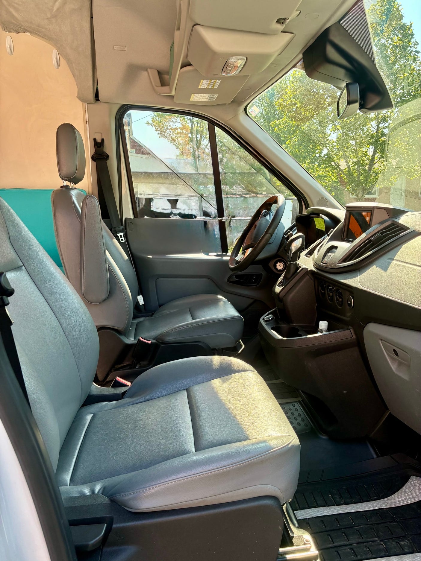 Spacious light gray front cabin of an rv rental van, featuring seats, dashboard, and steering wheel.