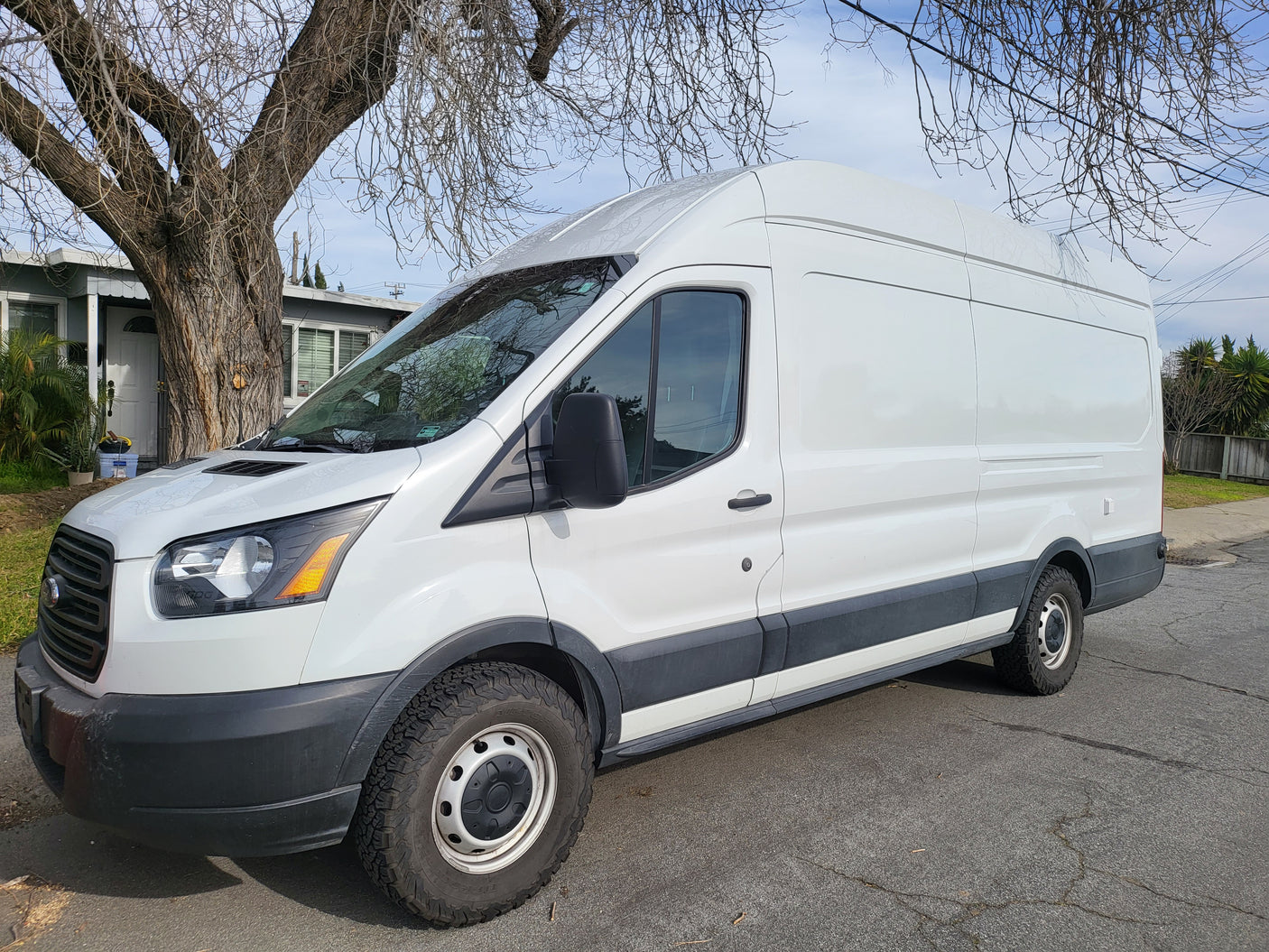 White Ford Transit high-roof van with all-terrain tires, ready for an RV rental adventure.