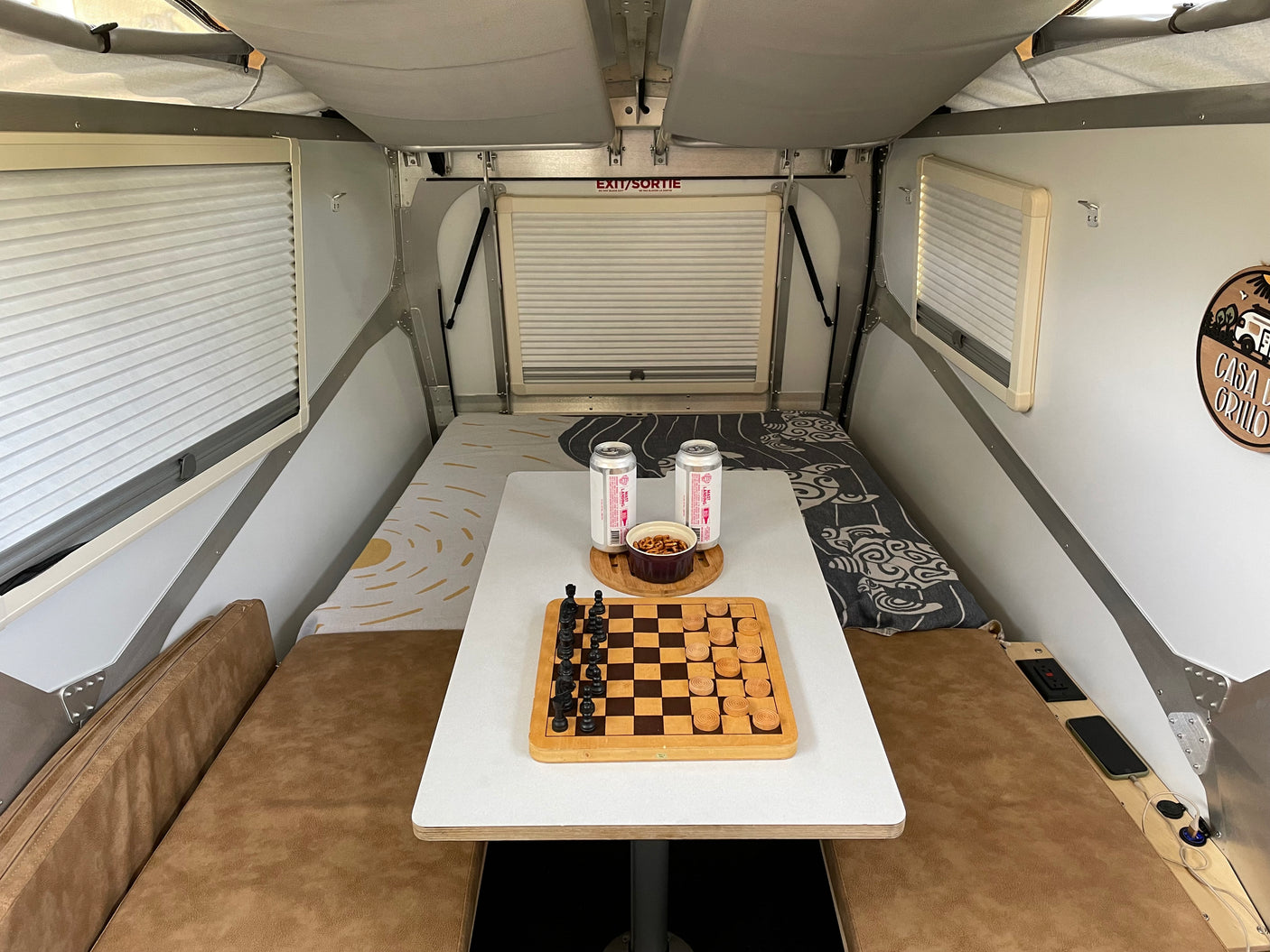 This RV rental's inviting interior features a dining table with chess & snacks, beds, and charging outlets.