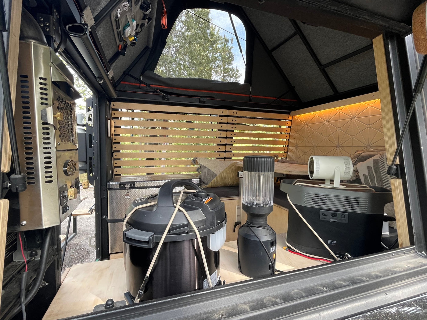 Inside an RV rental, showing a functional and organized camper setup with portable power, kitchen gear, and entertainment. — photo 16