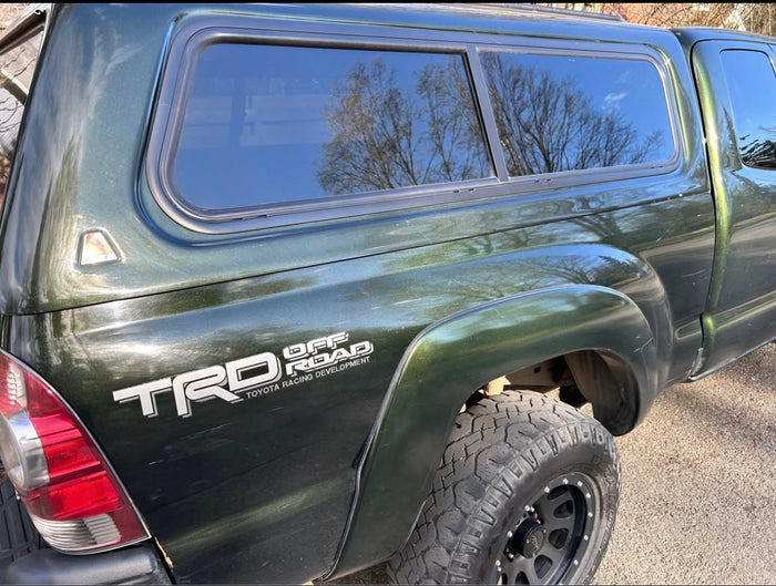 Green Toyota Tacoma TRD Off Road pickup truck with a matching camper shell, ready for an rv rental adventure.