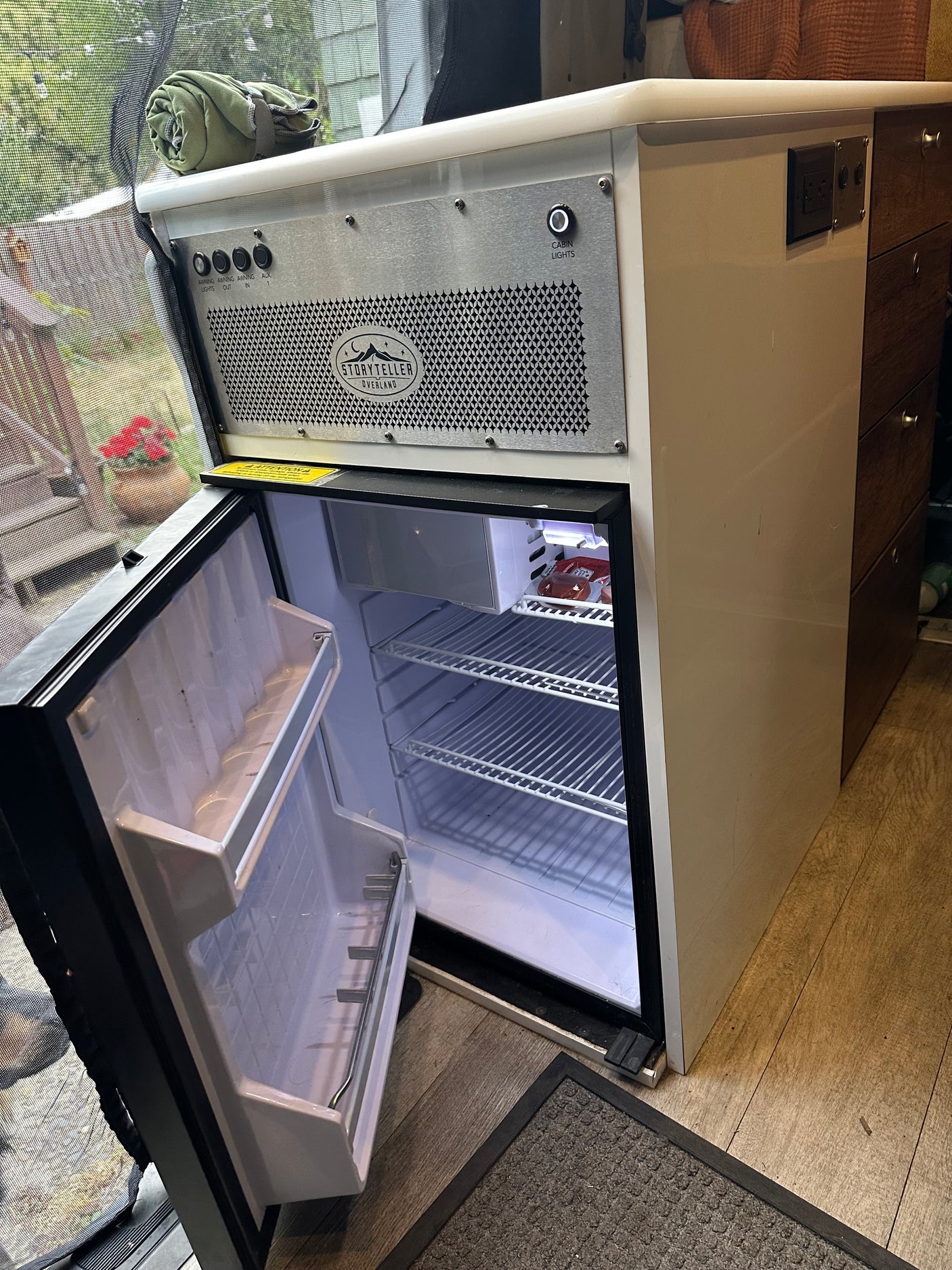 Inside an RV rental: an open refrigerator, control panel, and drawers for efficient camper storage. Ready for your trip!